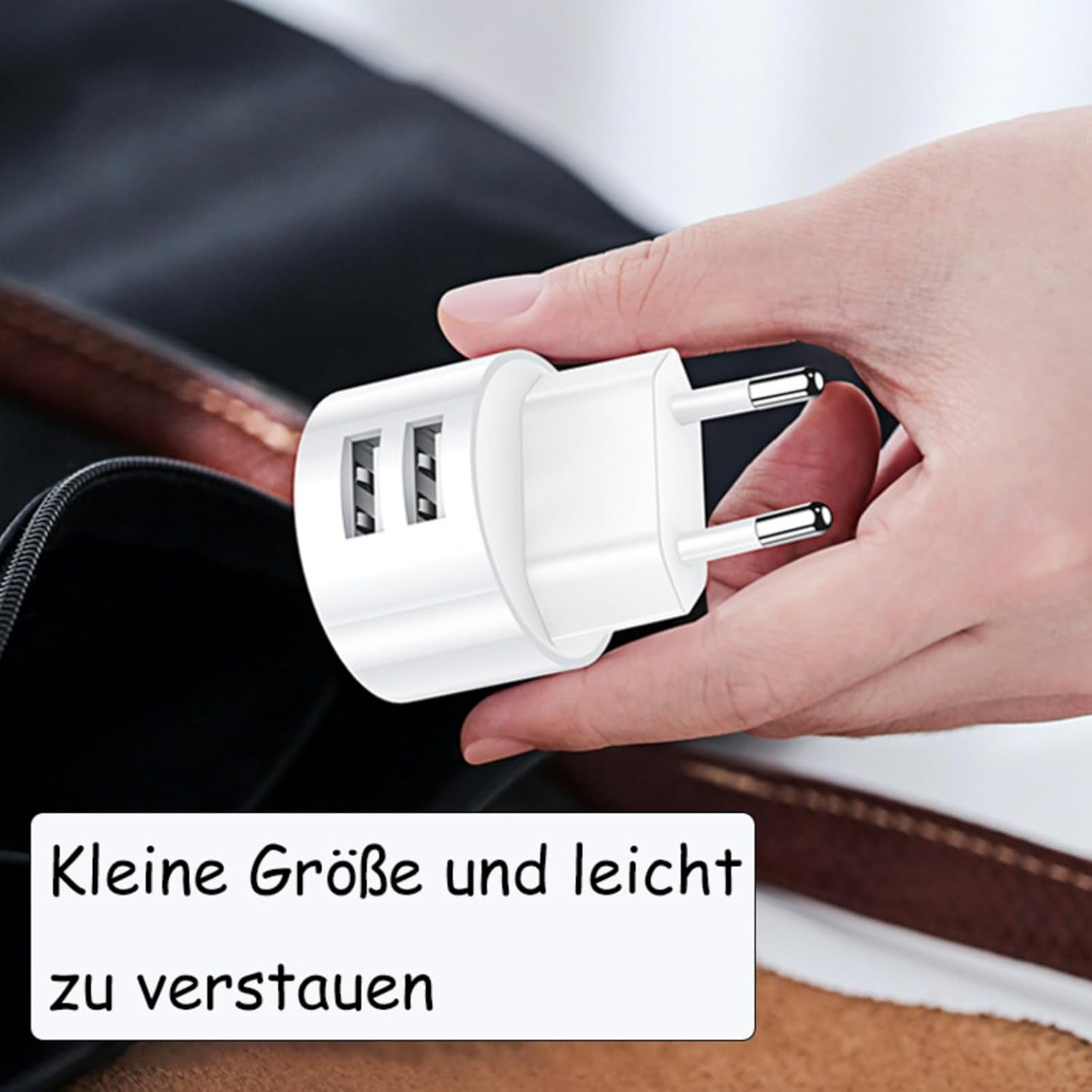 Weiße Reiseadapter mit zwei USB-Anschlüssen, gehalten von einer Hand.