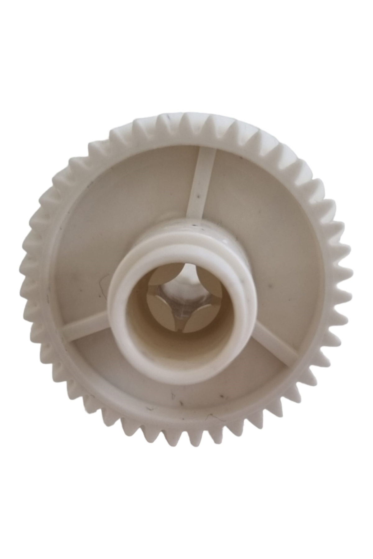 Merkezinde açıklığı ve kenarında dişleri olan beyaz plastik dişli.