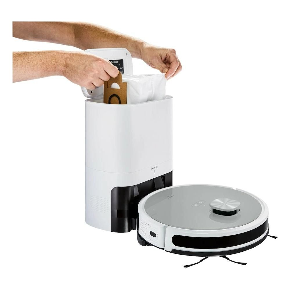 Mężczyzna wkłada worek na kurz do białej stacji ładującej robota sprzątającego.