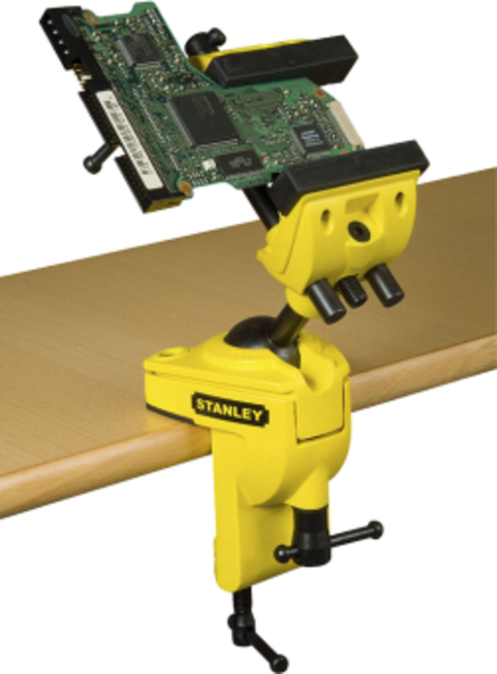 Ein gelber Stanley-Schraubstock hält eine Leiterplatte auf einem Holztisch.