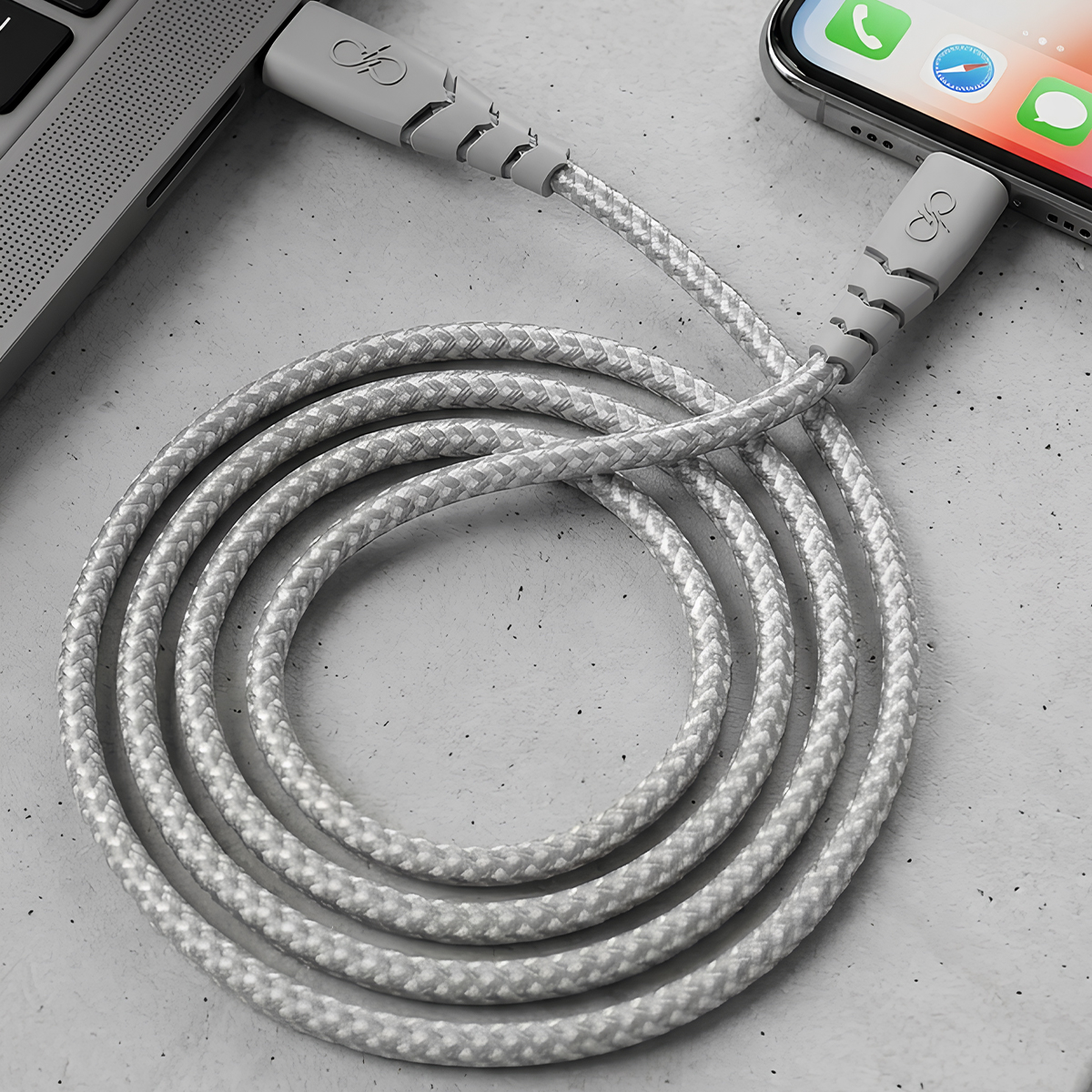 Un cavo di ricarica grigio collega un laptop e uno smartphone.