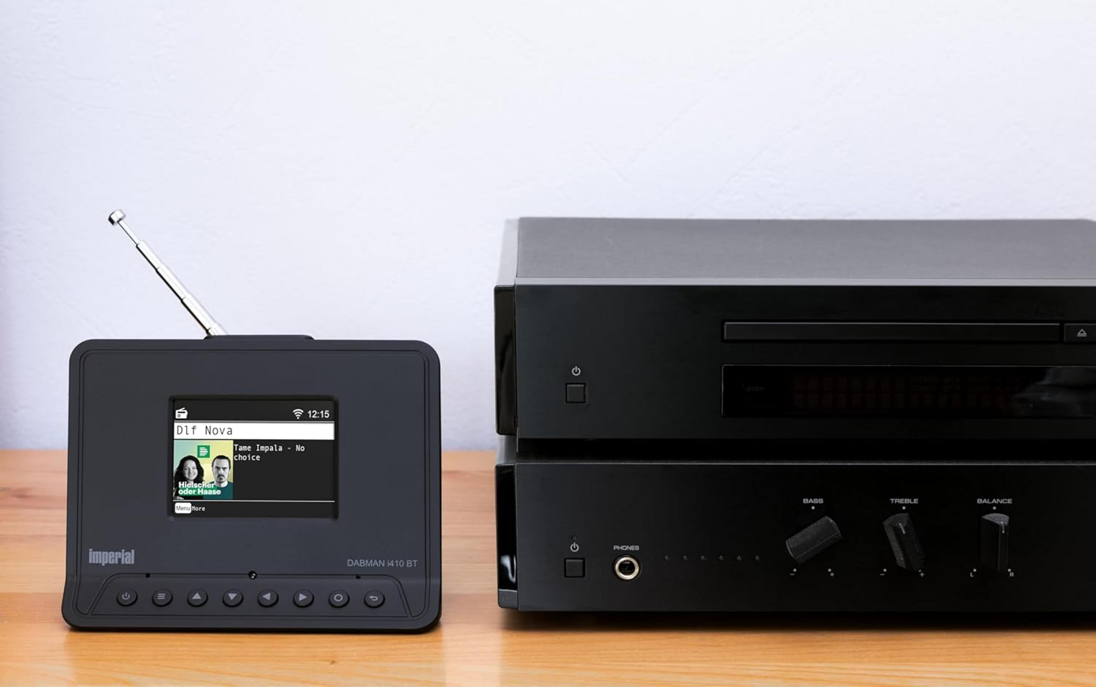 Czarna radioodbiornik DAB i wzmacniacz na drewnianym stole.