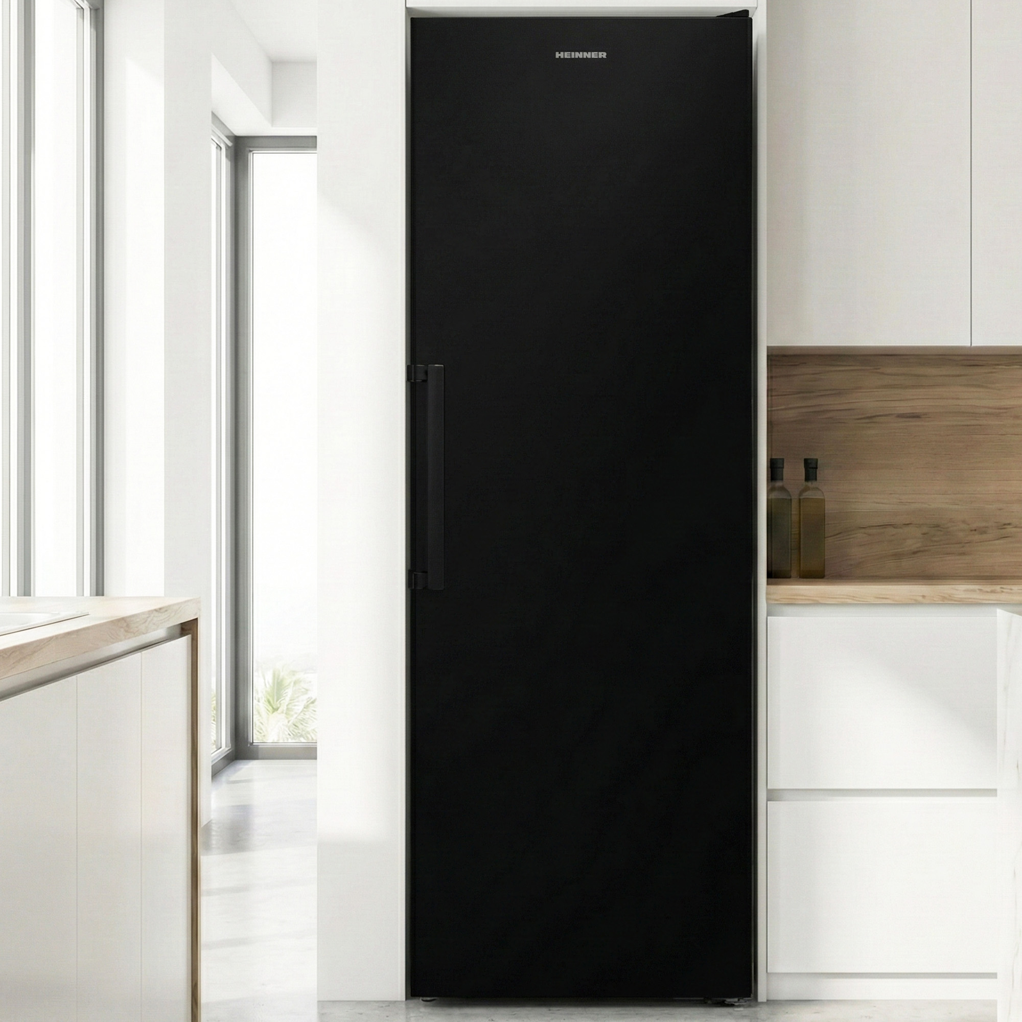 Réfrigérateur noir avec poignée noire, à côté de placards blancs et parquet.