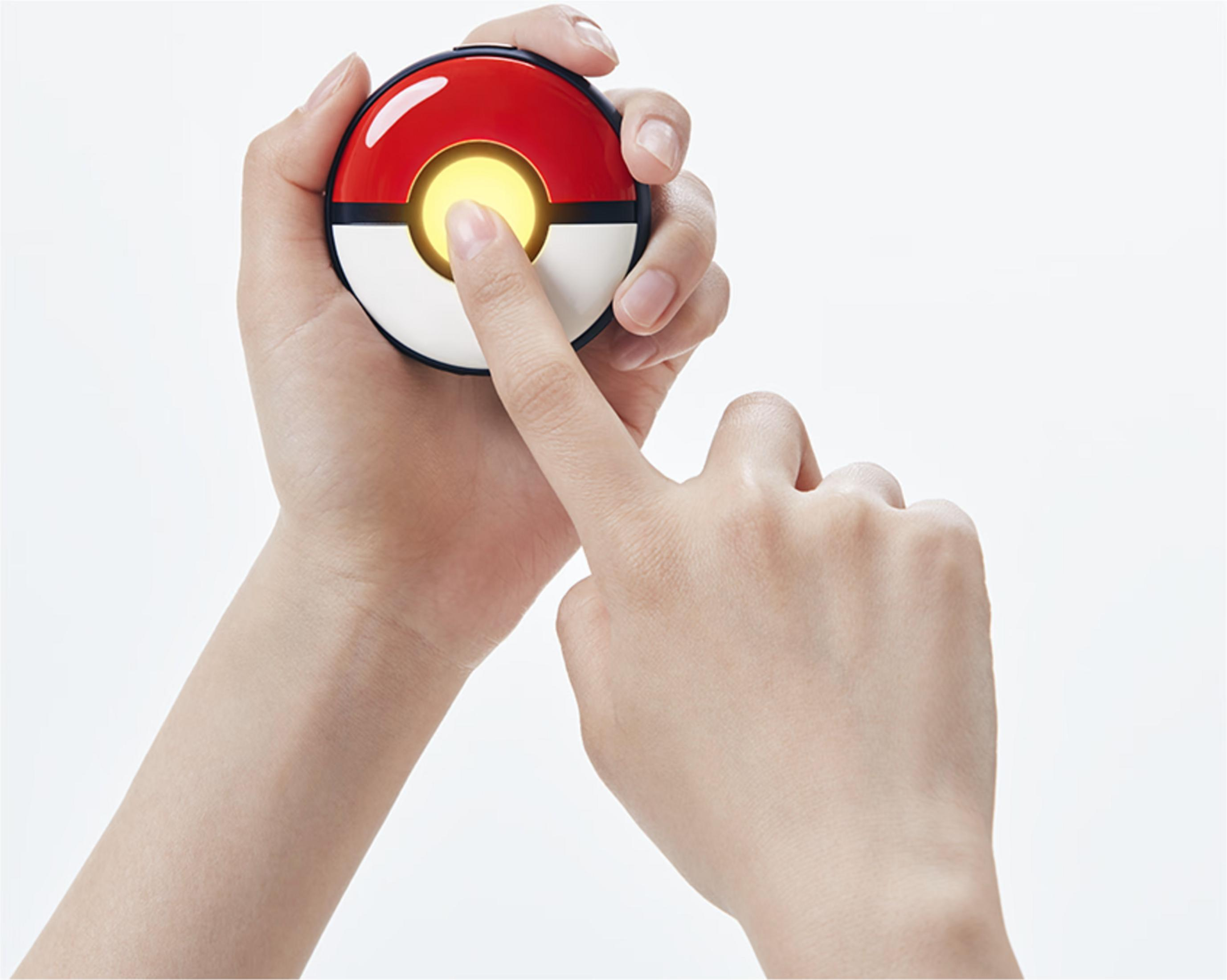 Dłoń trzyma świecącą Poké Balla, palec dotyka środka.