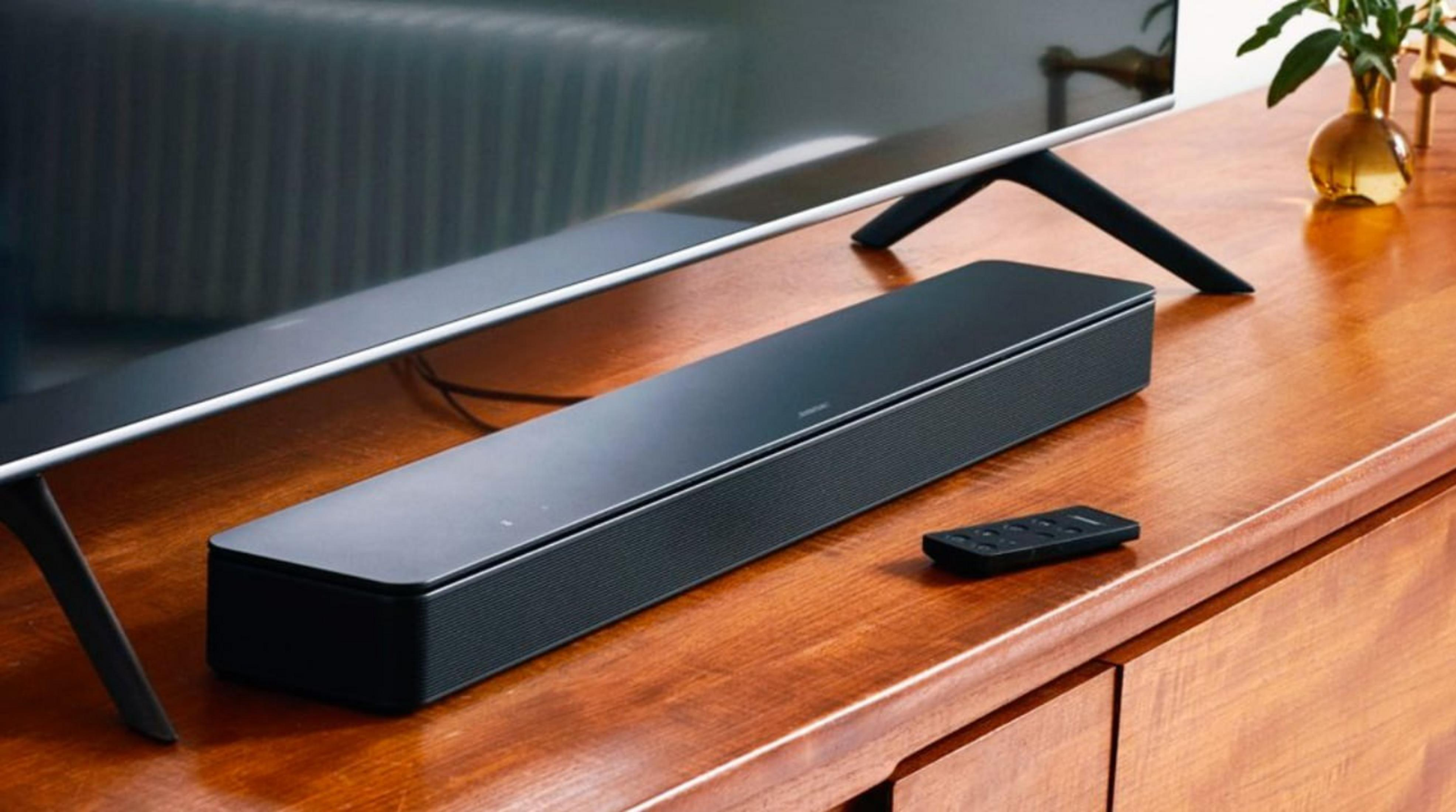 Ein schwarzer Soundbar und Fernbedienung auf einem Holzmöbel.