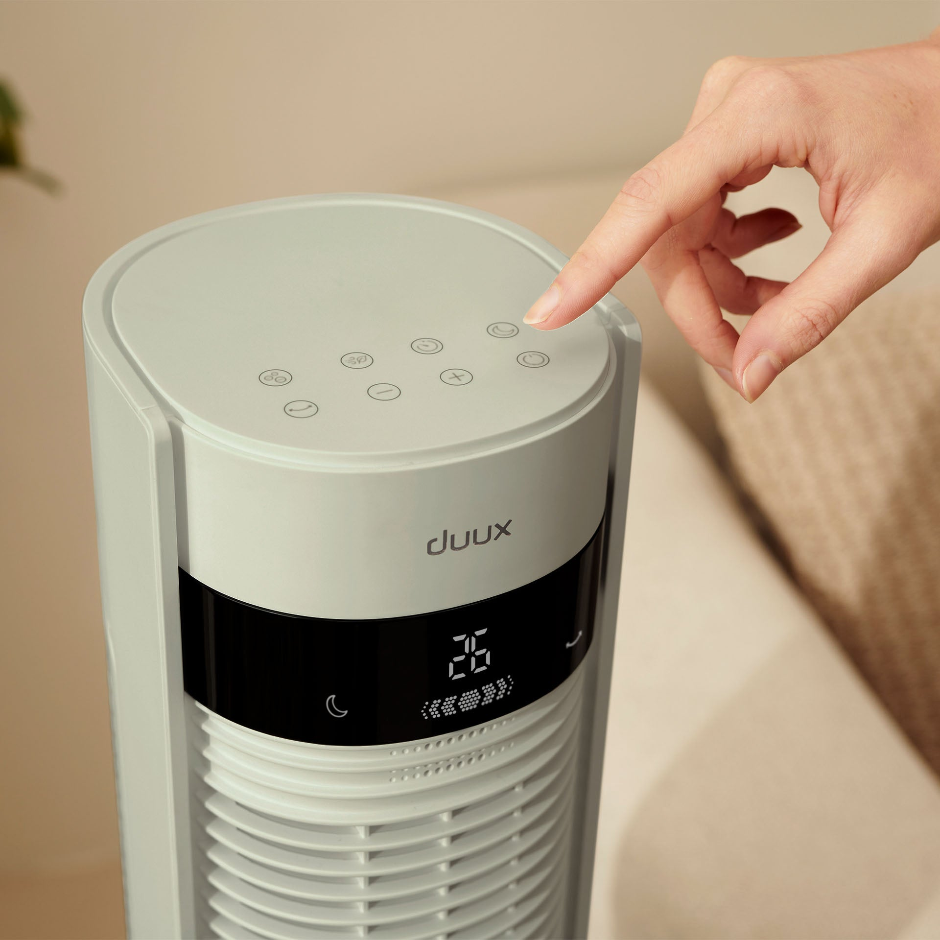 Een hand drukt op een knop van een witte ventilator met digitaal display.