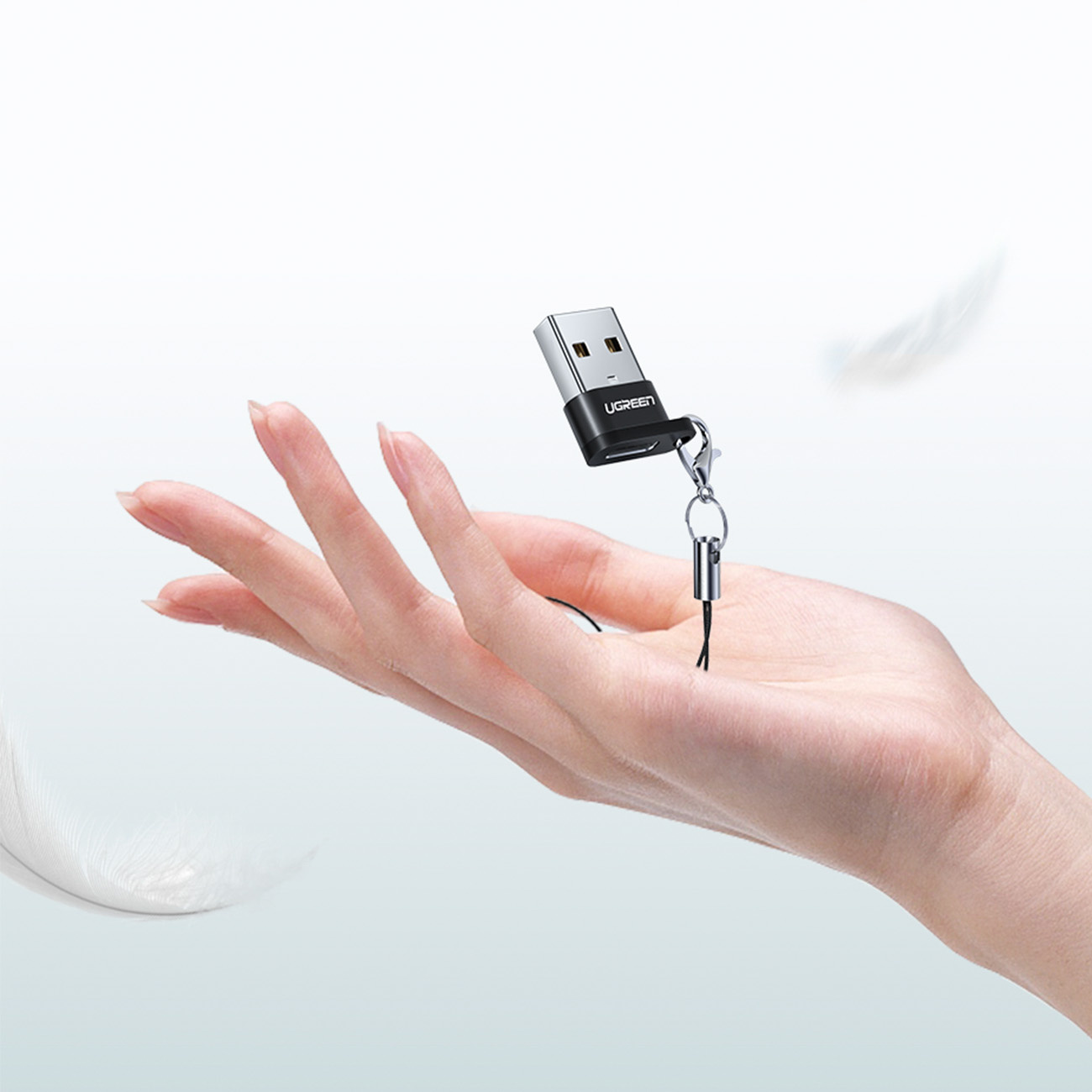 Bir el, kordonlu küçük siyah ve gümüş renkli bir USB bellek tutuyor.
