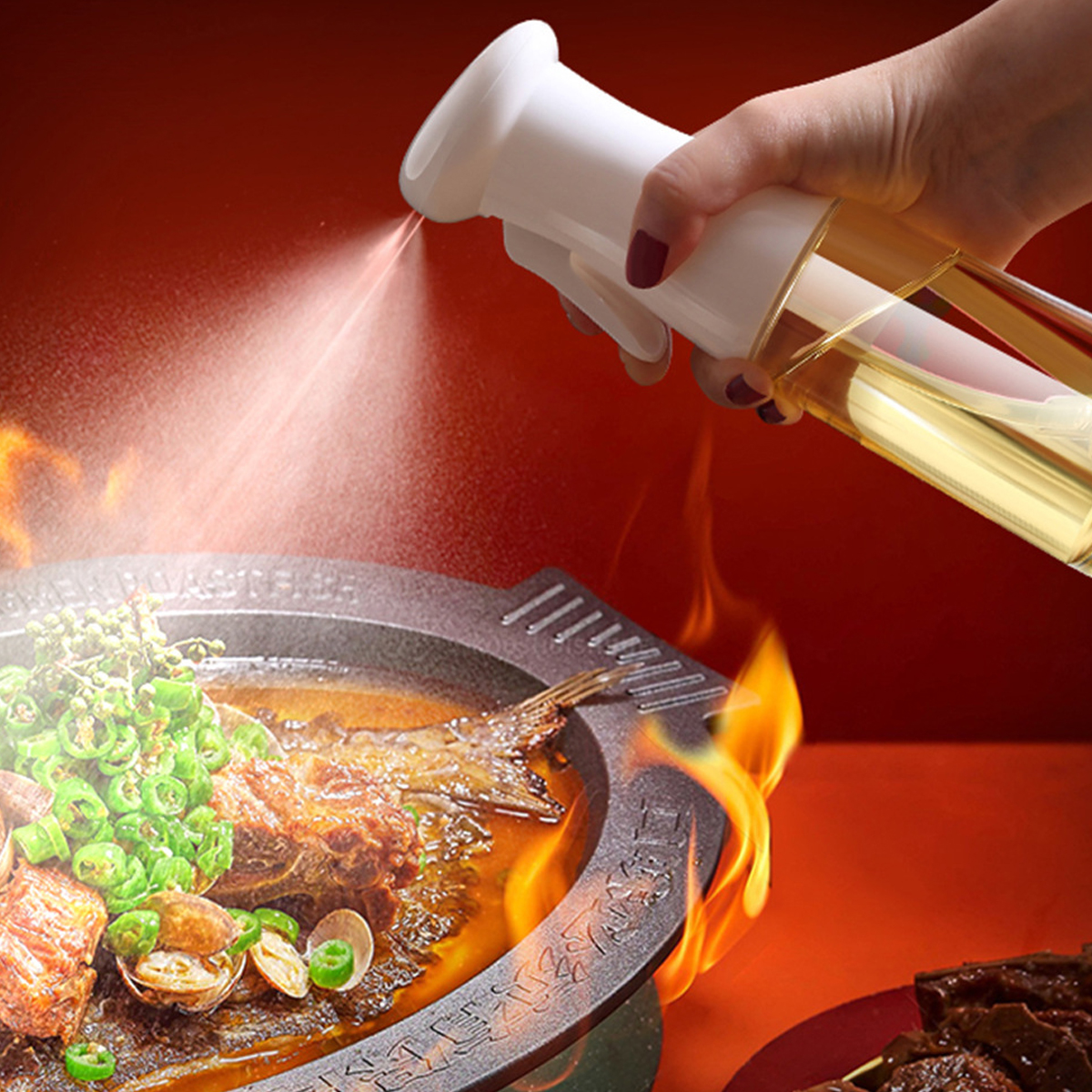Ein Sprüher mit Öl besprüht ein Gericht mit Fisch und Gemüse in Flammen.