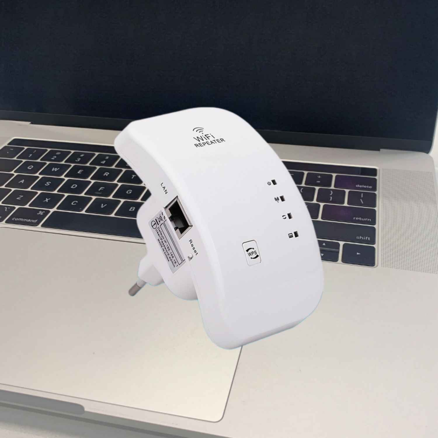 Ein weißer WLAN-Repeater liegt auf einer Laptop-Tastatur.