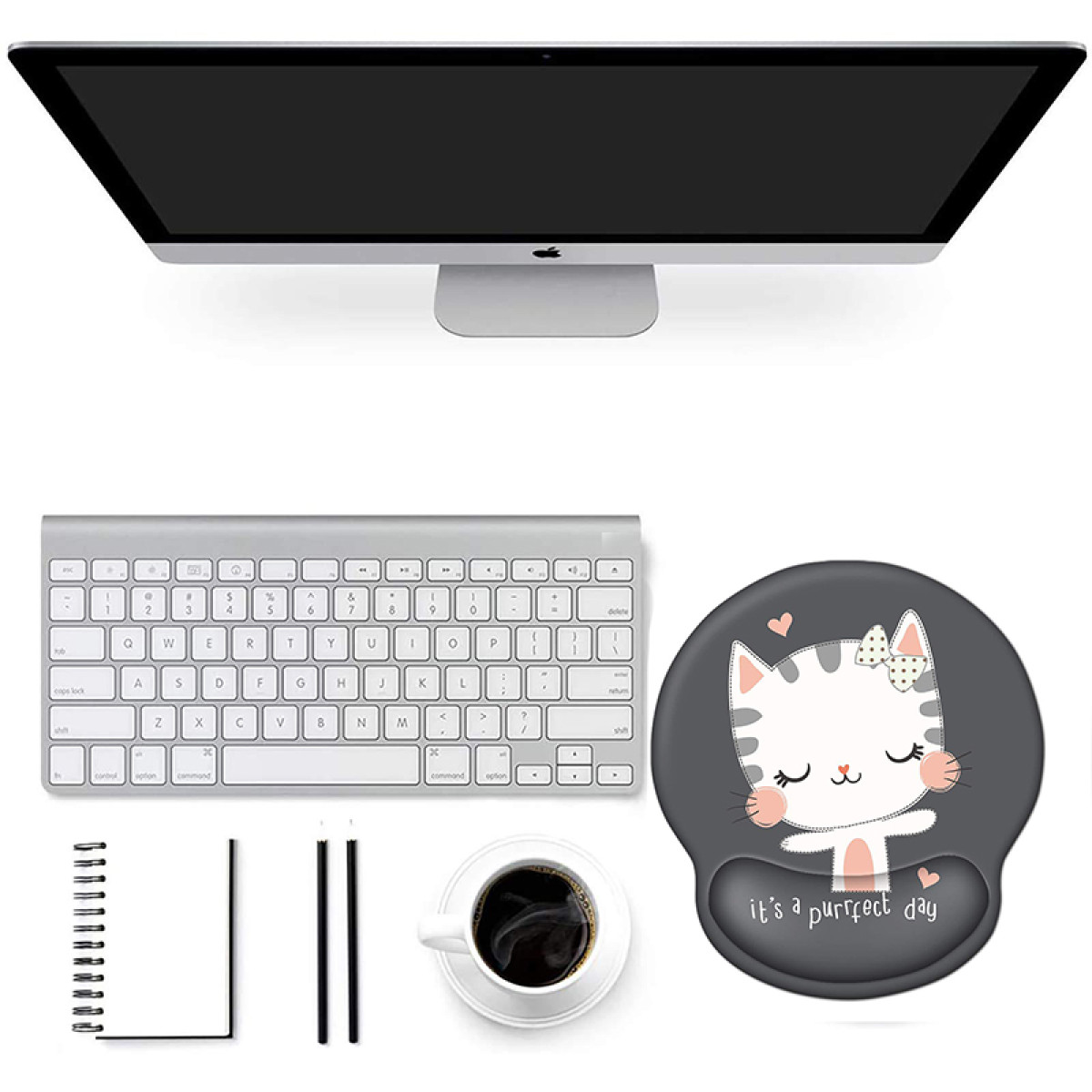 Biurko z monitorem Apple, klawiaturą, podkładką pod mysz z kotem, notatnikiem, ołówkami i kawą.