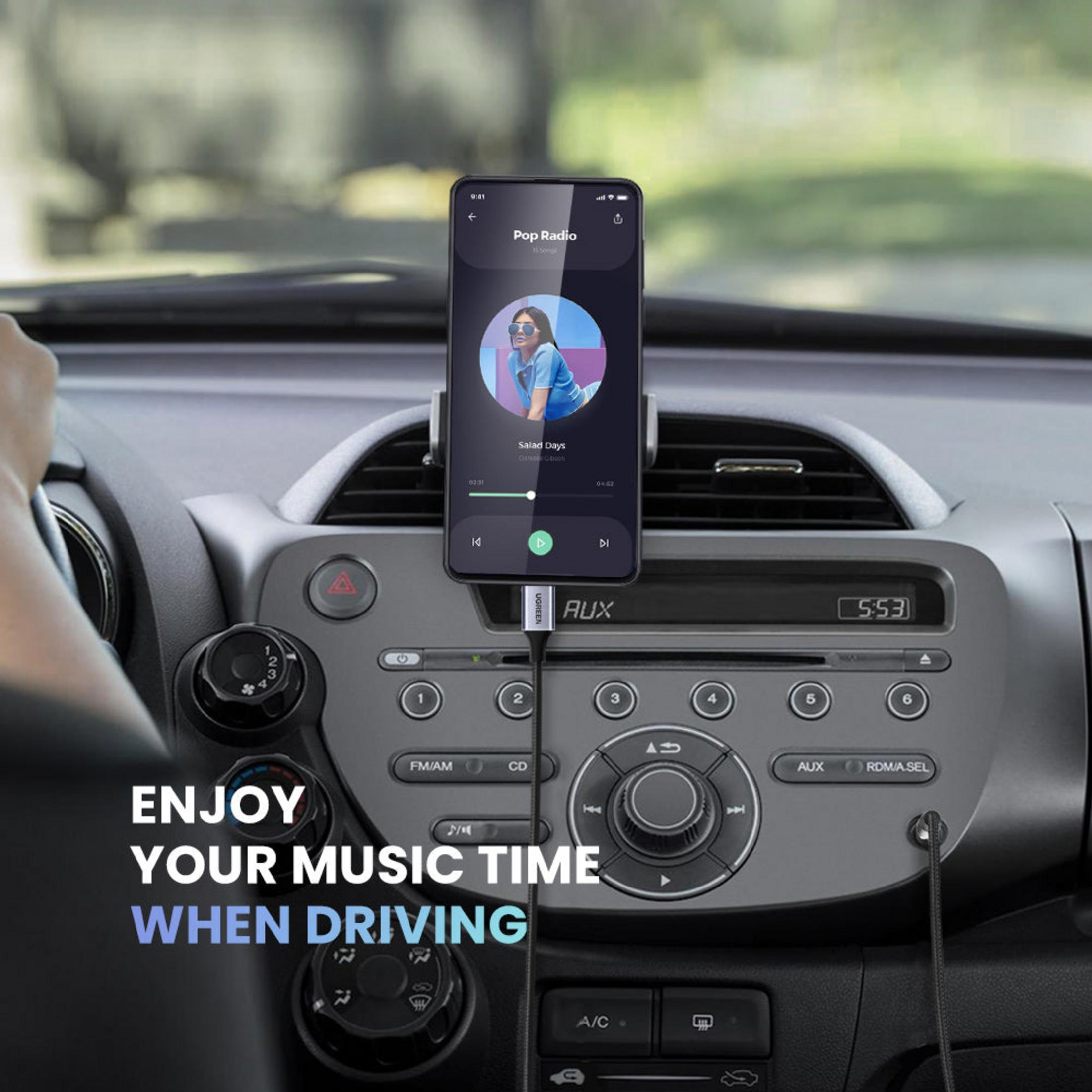 Dłoń trzyma kierownicę, telefon odtwarza muzykę w samochodzie. "Enjoy your music time when driving".