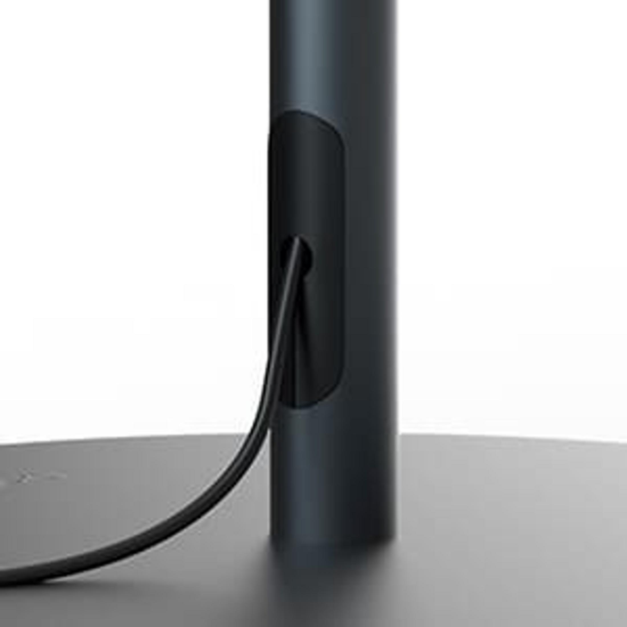 Un cable negro sale de un soporte negro en un soporte oscuro.