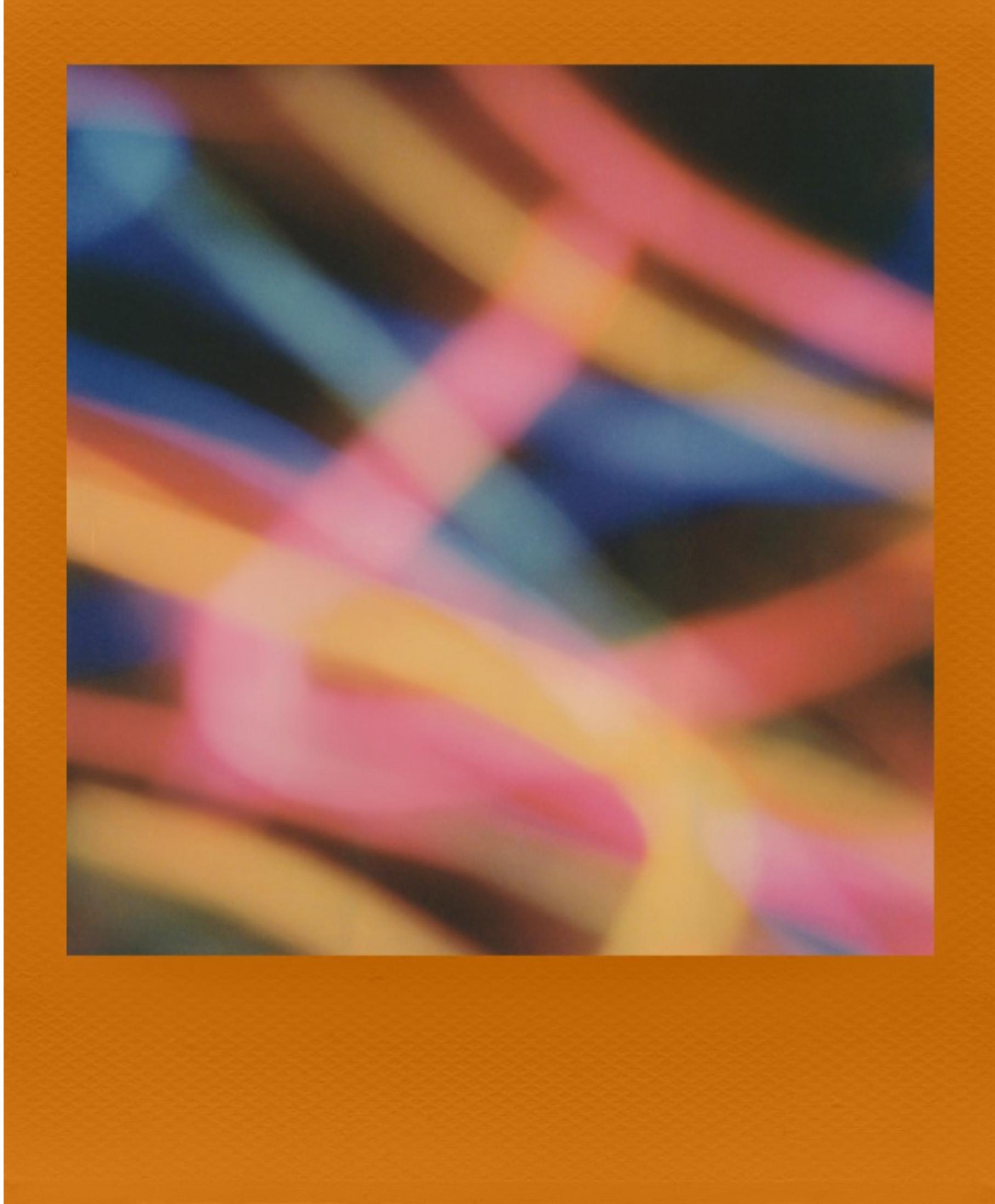 Rayas abstractas de luz en rosa, naranja y azul sobre fondo oscuro.