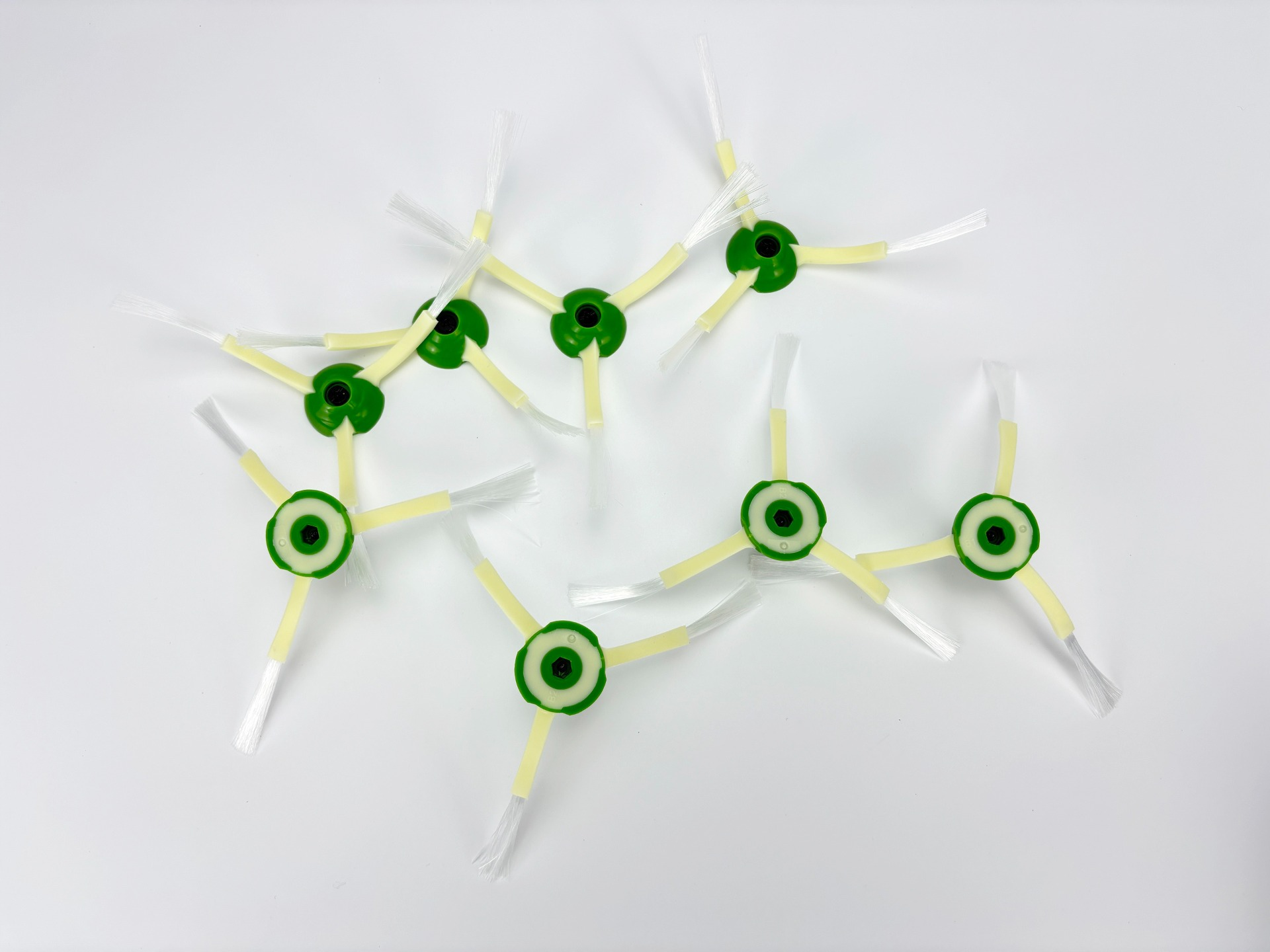 Kilka zielonych szczotek do odkurzacza z żółtymi ramionami i białym włosiem na białym tle.