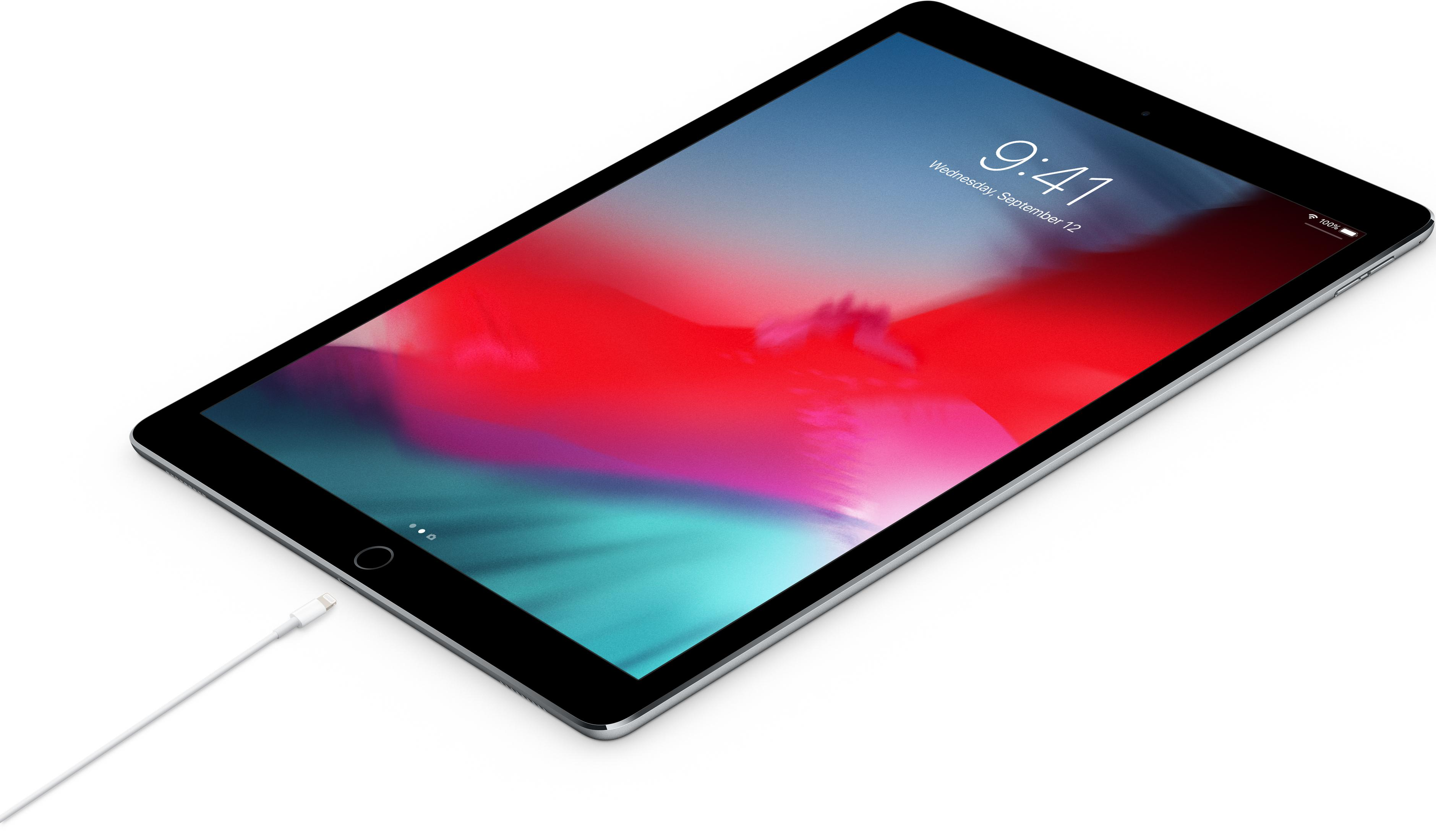 Srebrny iPad z podłączonym kablem ładującym wyświetla ekran blokady.