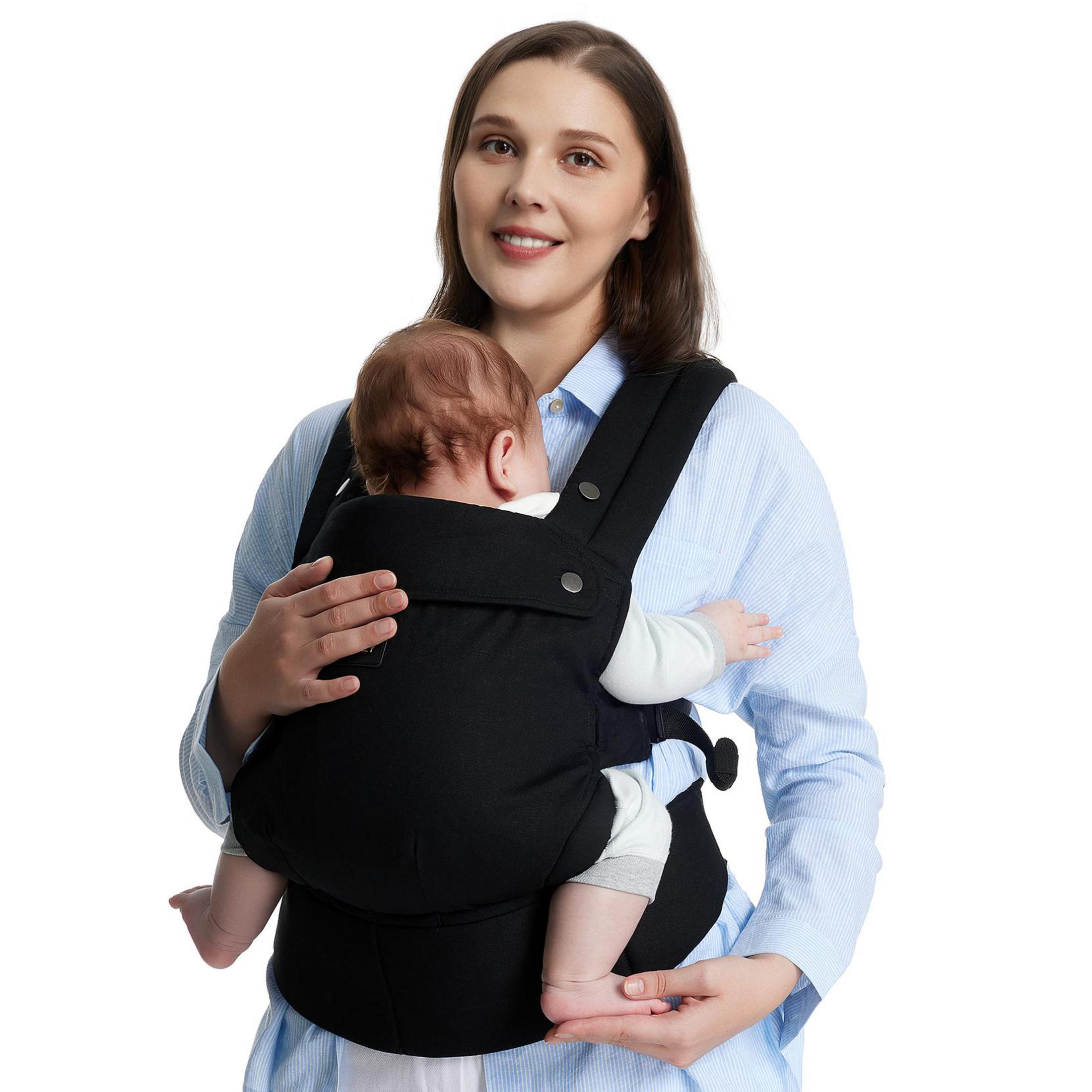 Mujer con bebé dormido en portabebés negro.