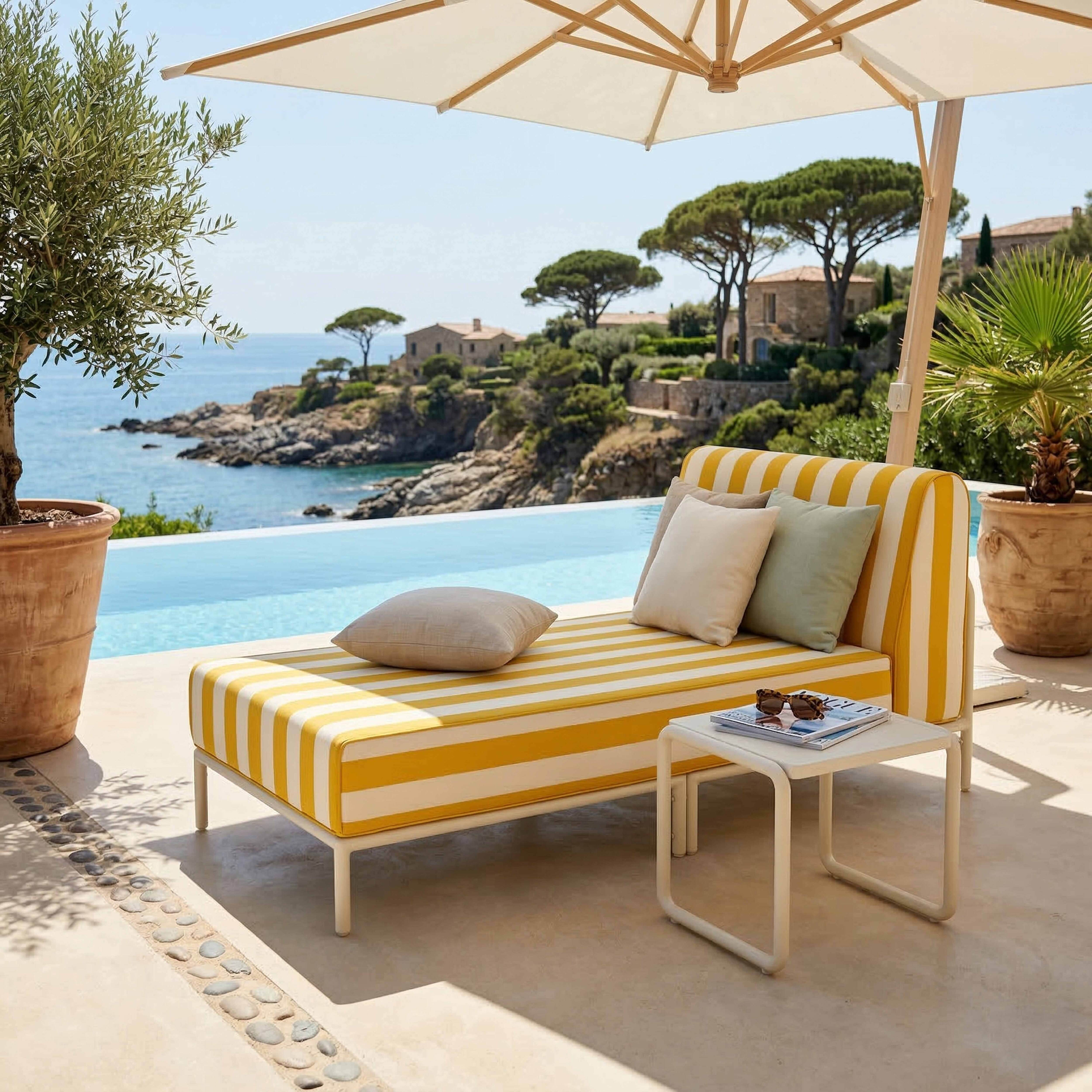 Ein gestreiftes Liegemöbel am Pool mit Blick auf das Meer und ein Dorf.
