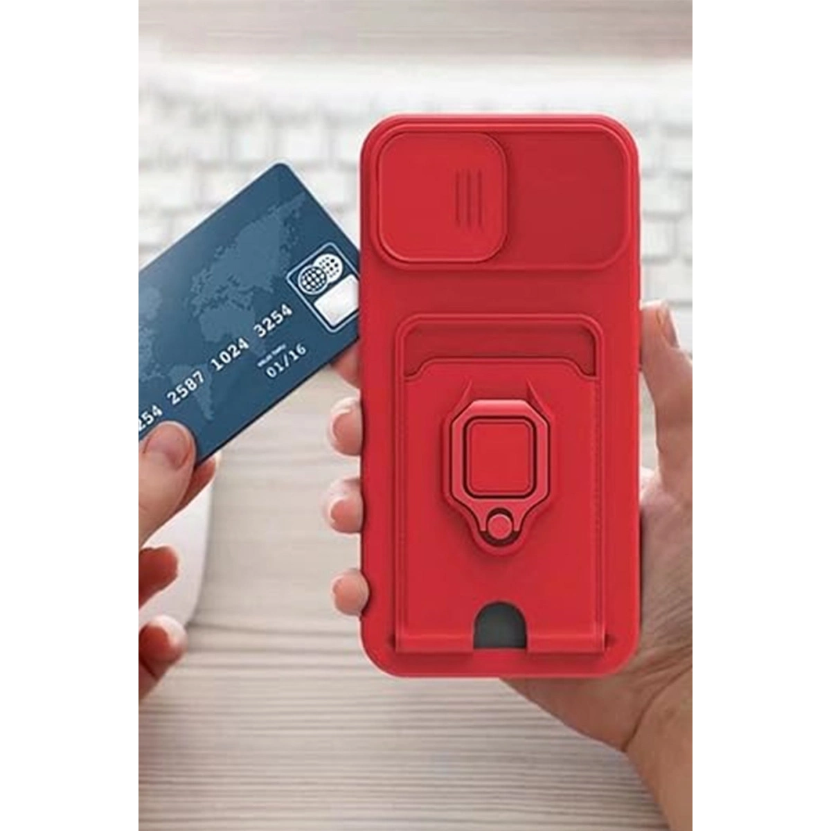 Kart yuvalı ve stantlı kırmızı telefon kılıfı, yanında mavi kredi kartı.