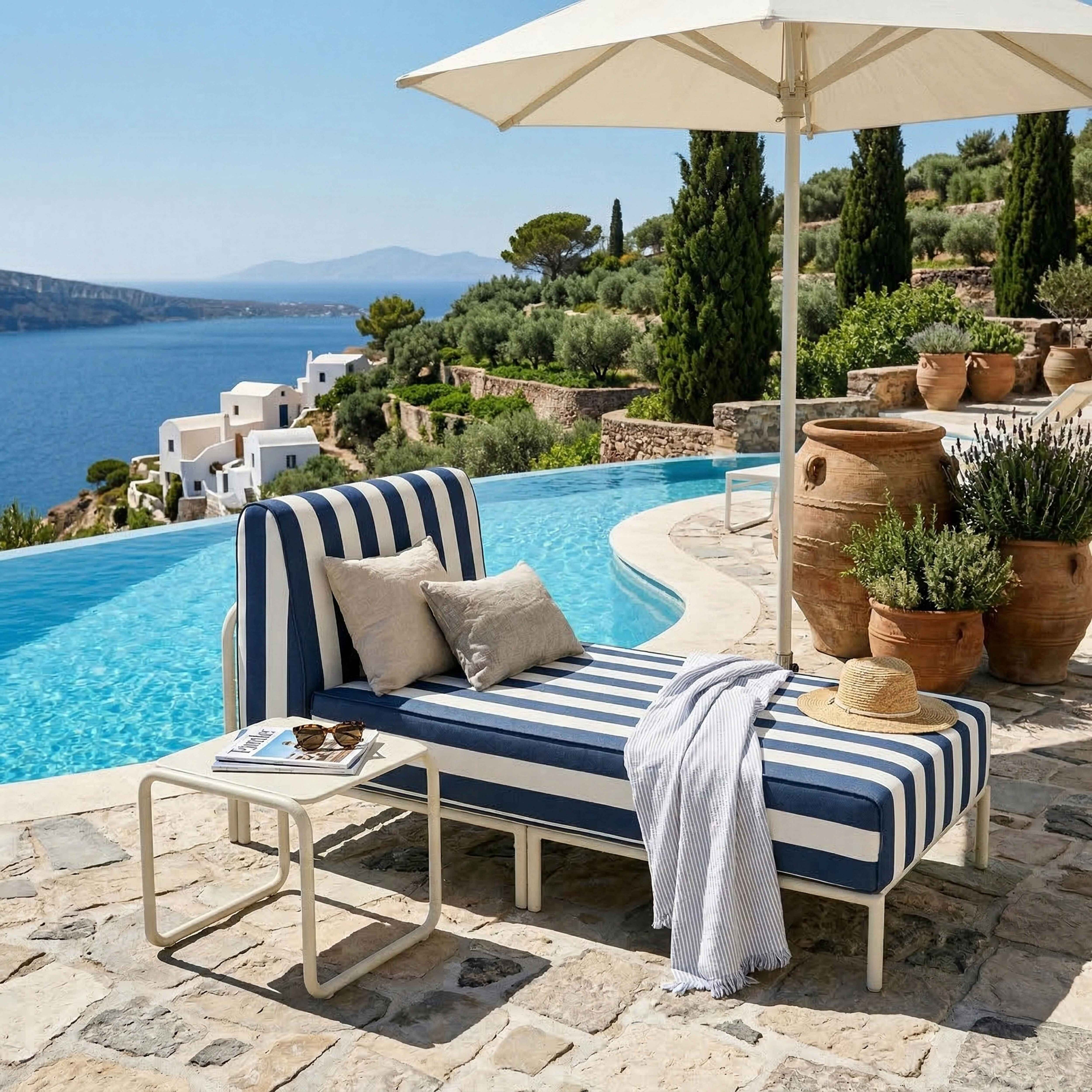 Eine gestreifte Liege am Pool mit Blick aufs Meer, Sonnenschirm, Kissen und Töpfe.