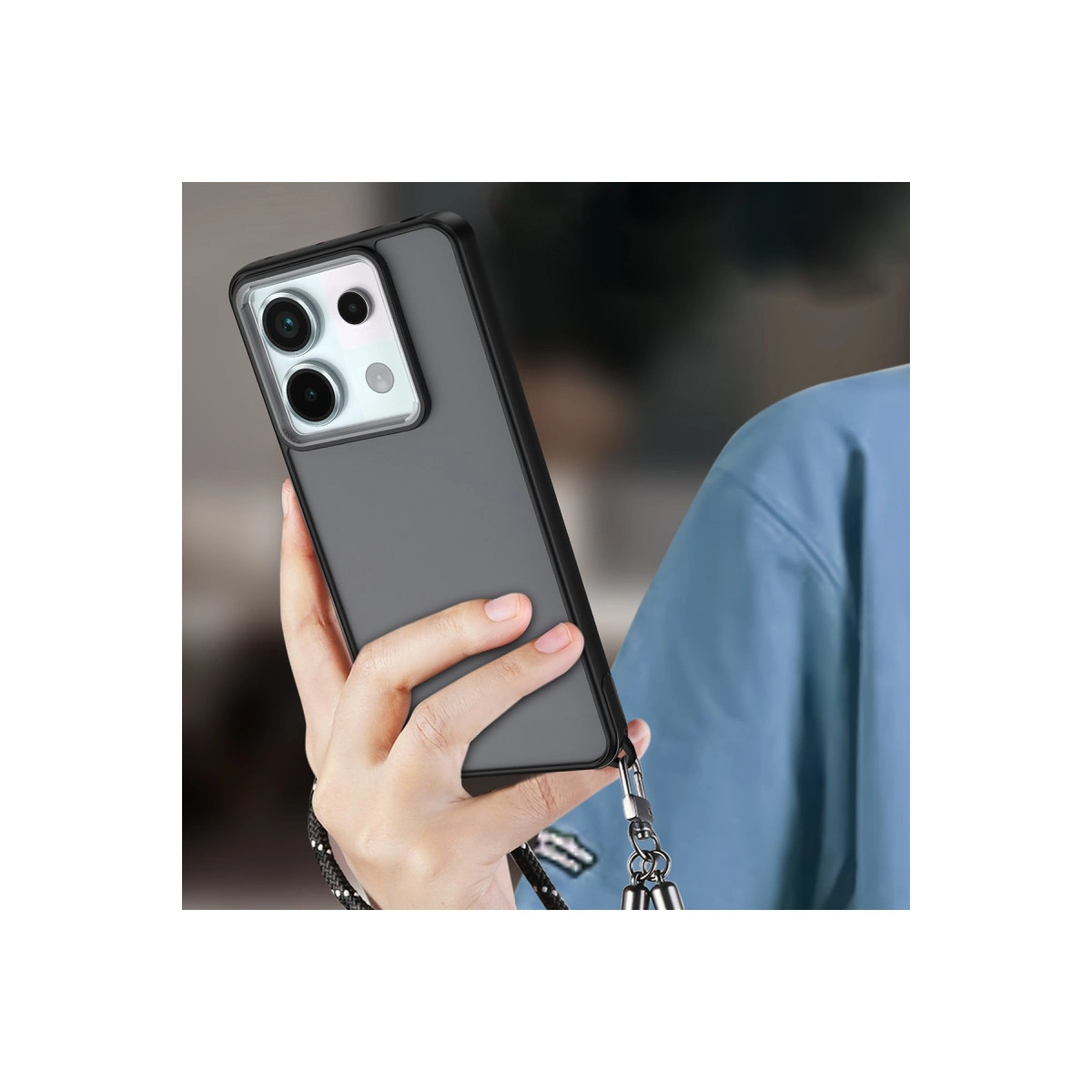 Elinizde şeffaf kılıflı ve siyah askılı koyu gri bir telefon tutuluyor.