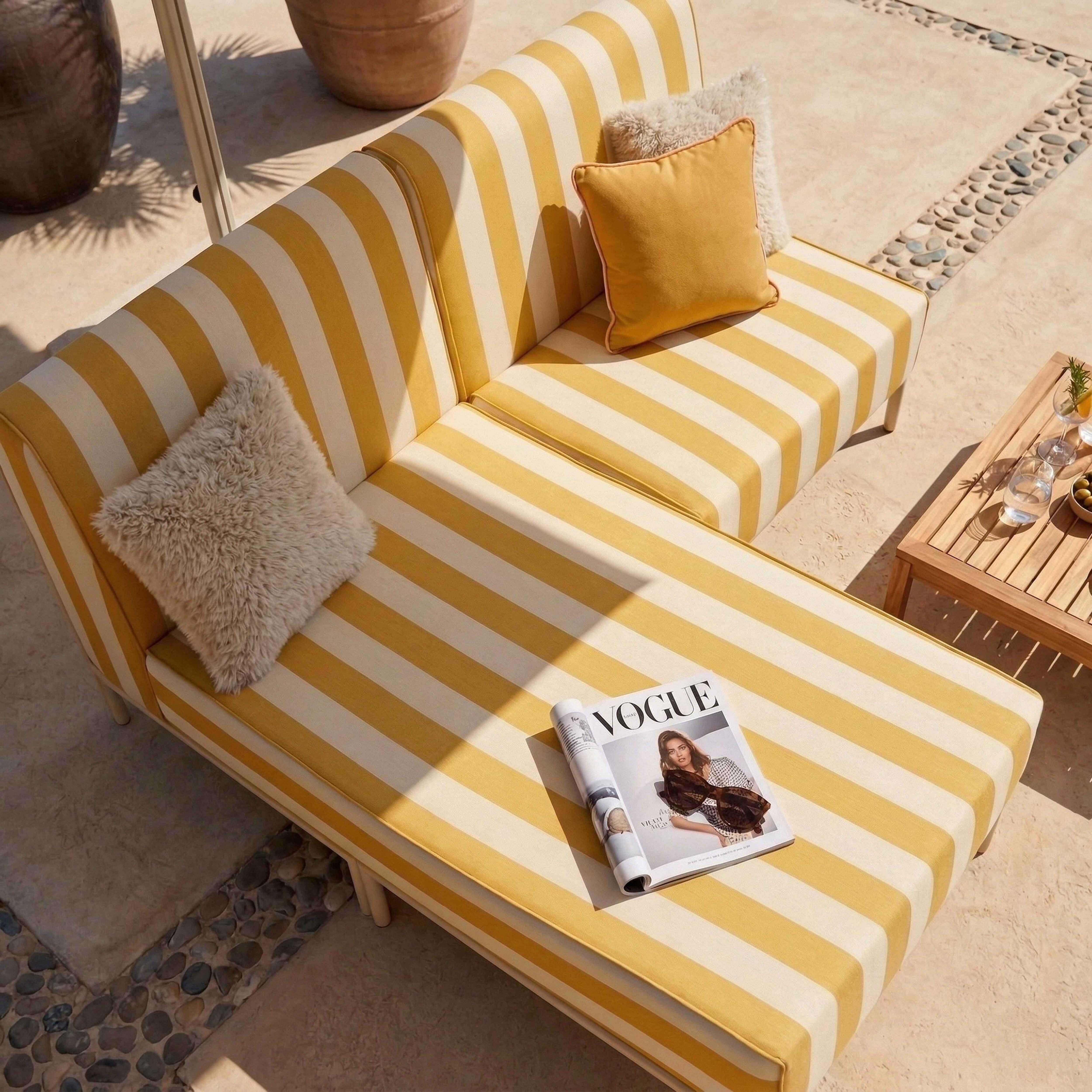 Gestreifte Couch mit Kissen und Vogue-Magazin auf einer Terrasse.