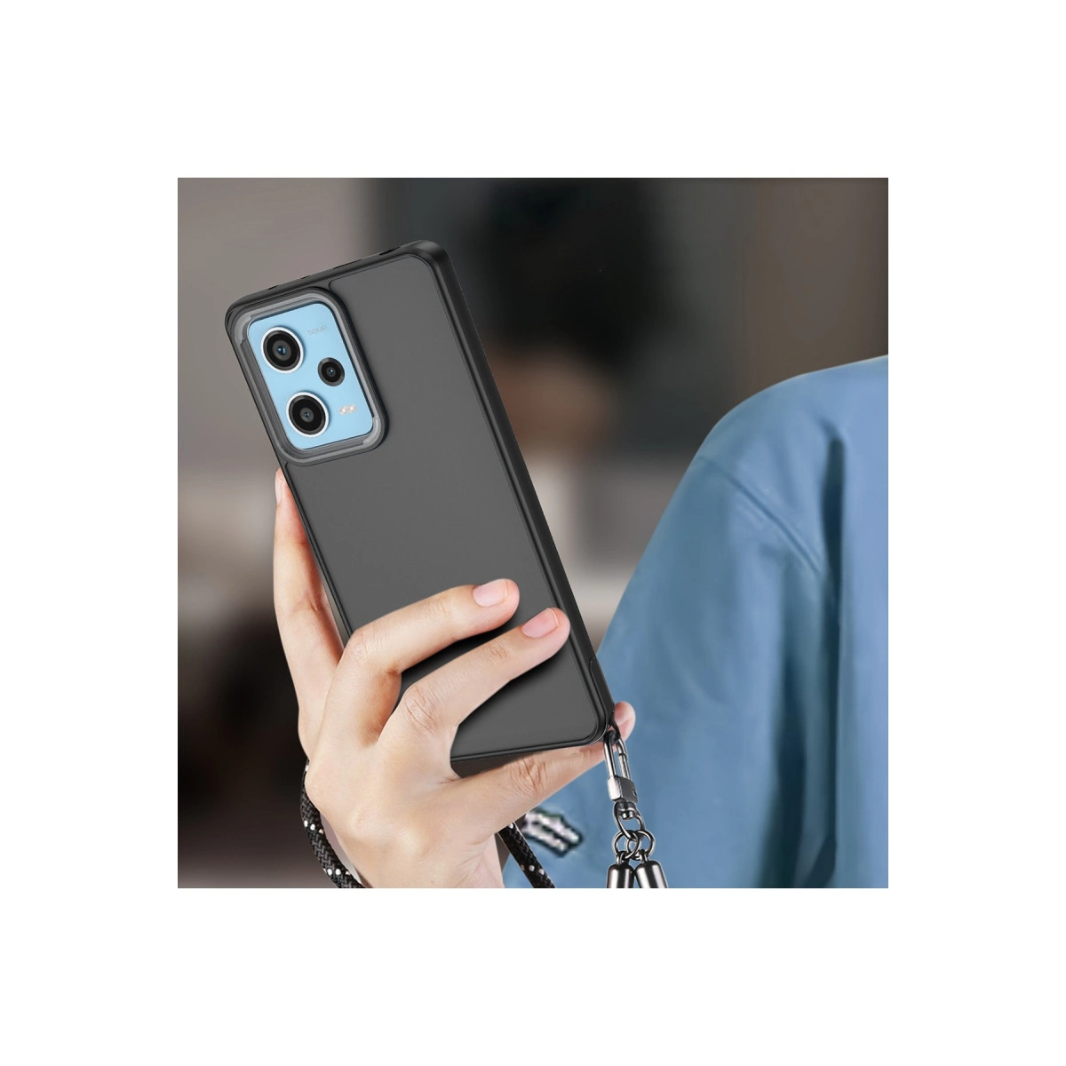 Bir el, üç kameralı ve kordonlu koyu renkli bir akıllı telefon tutuyor.