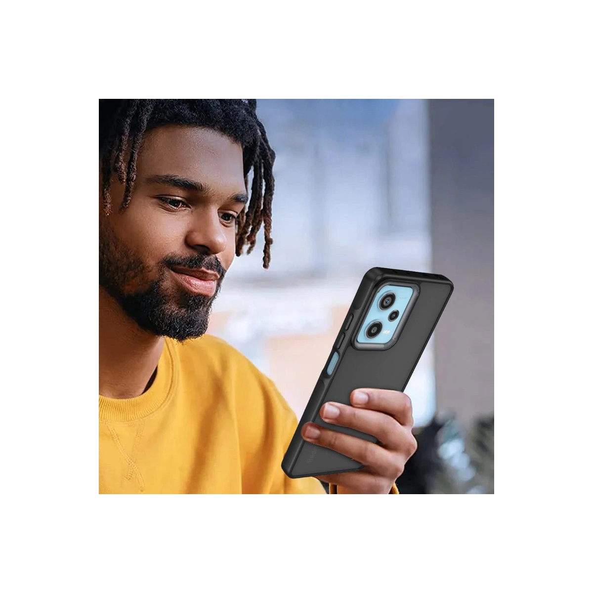 Sarı sweatshirt'lü adam üç kameralı siyah telefon tutuyor.