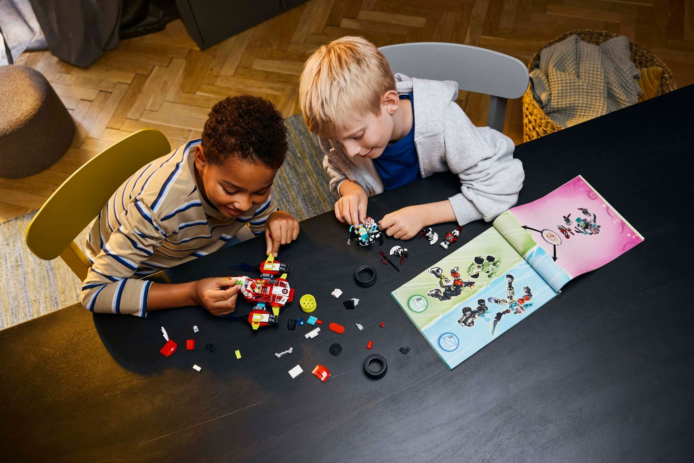 Zwei Jungen bauen ein rot-weißes Raumschiffmodell mit Legosteinen nach Anleitung.