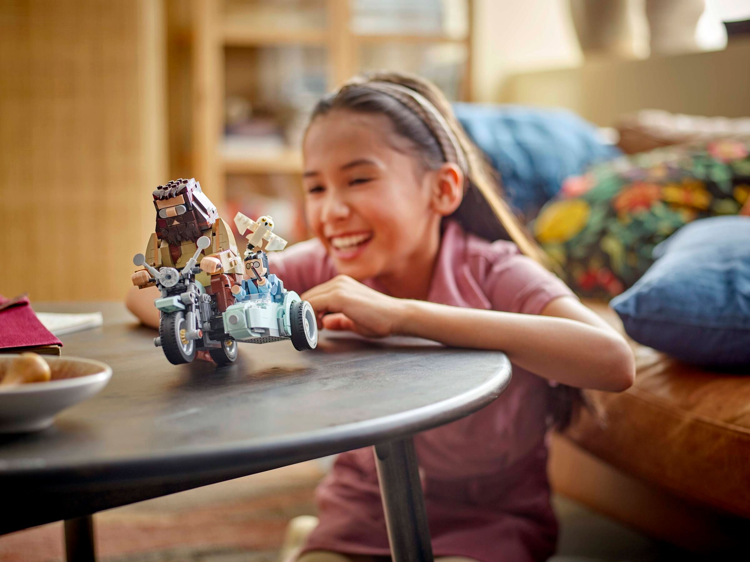 Ein Mädchen spielt mit einem Lego-Motorrad mit Beiwagen, auf dem Figuren sitzen.