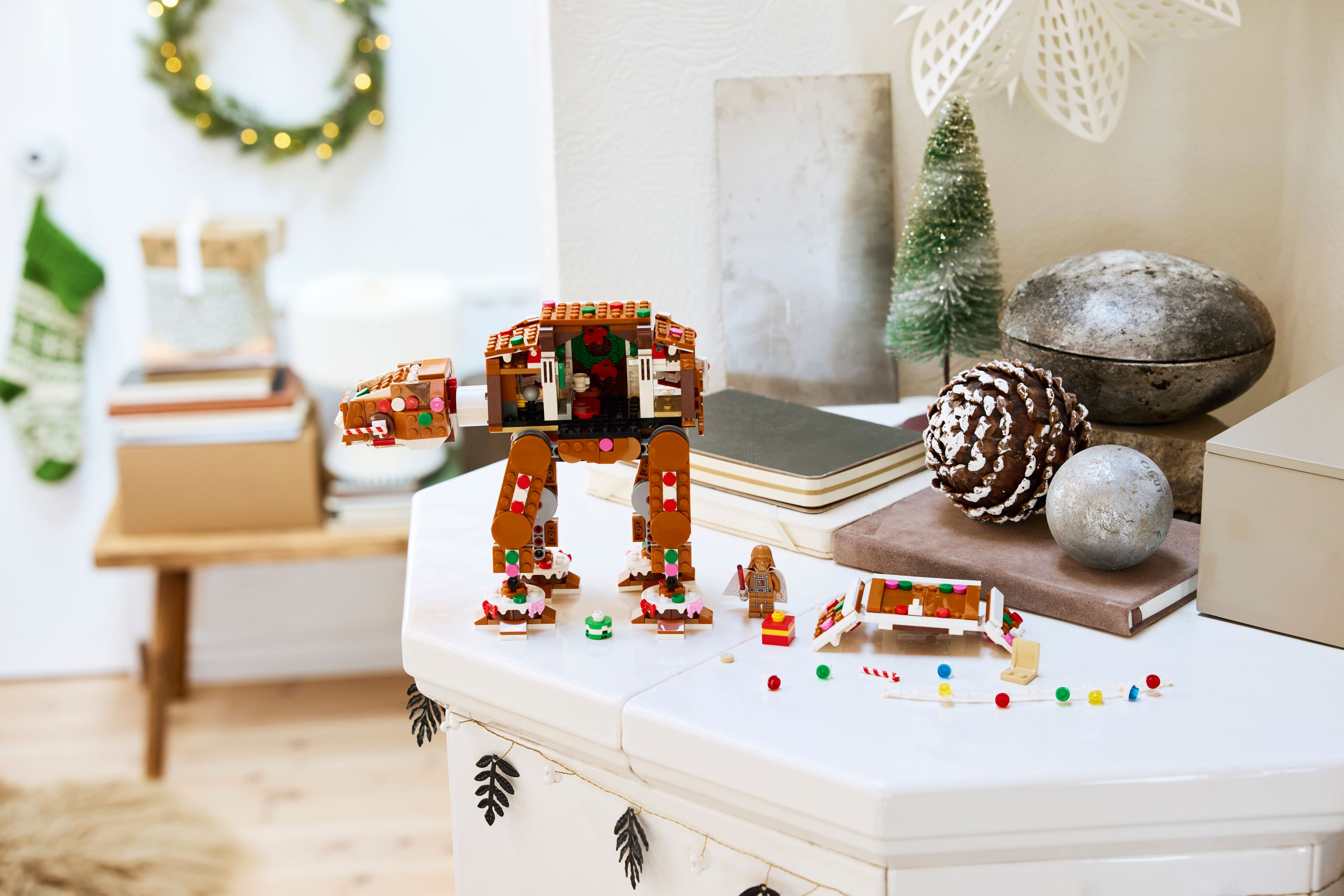 Noel temalı Lego AT-AT oyuncağı, süslemeli beyaz masada duruyor.
