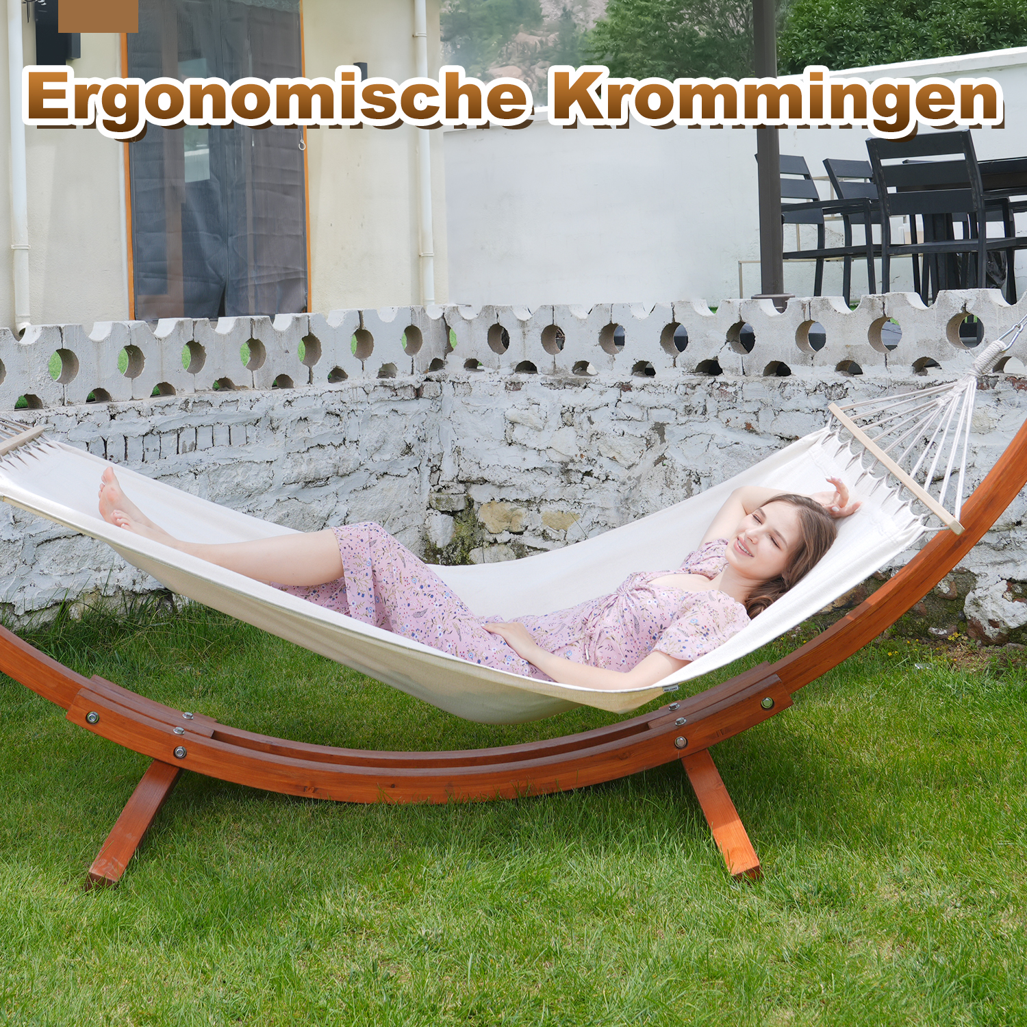 A woman relaxes in a hammock outdoors on green grass.