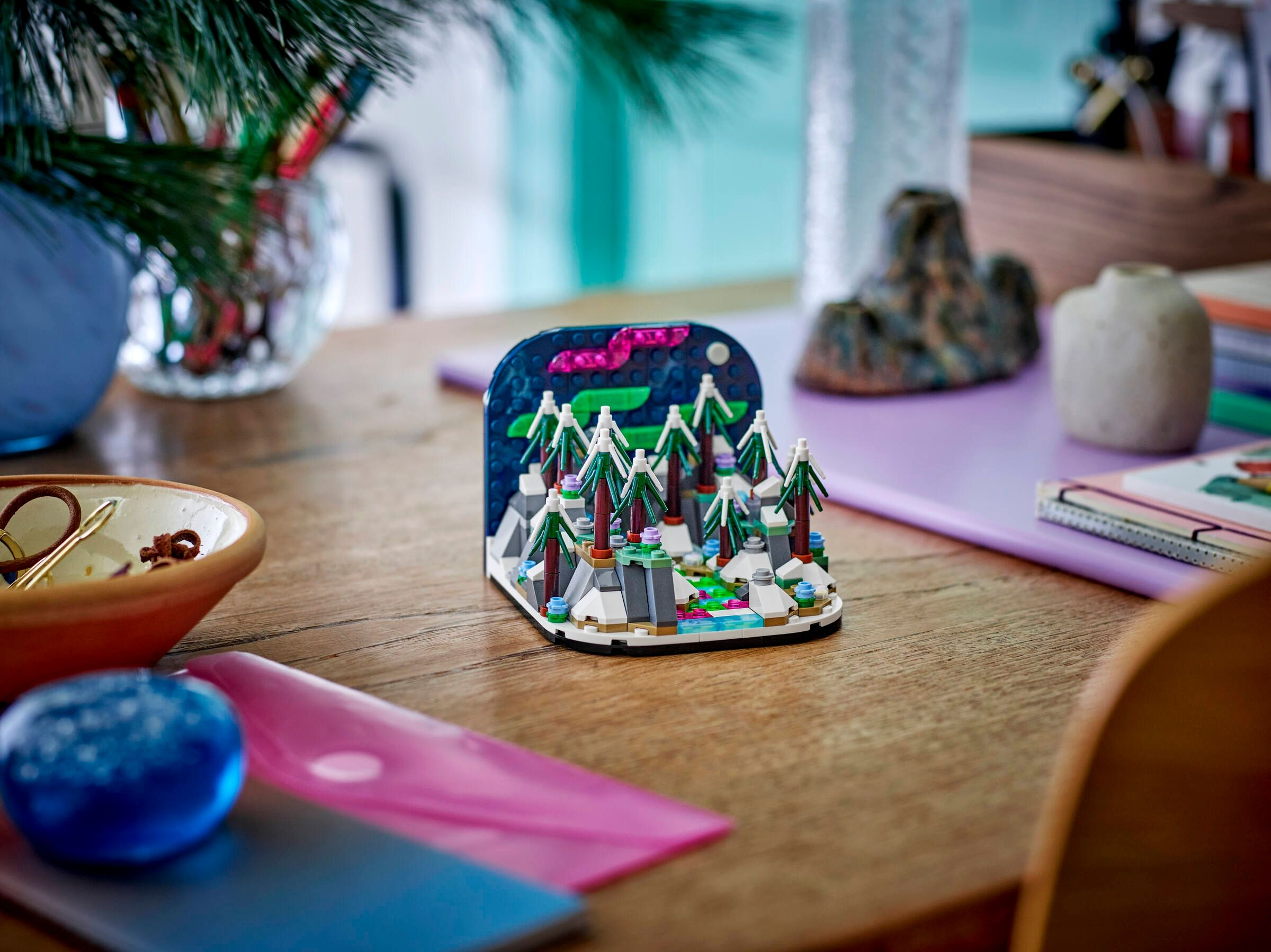 Modèle Lego d'une forêt avec aurore boréale et neige sur une table en bois.