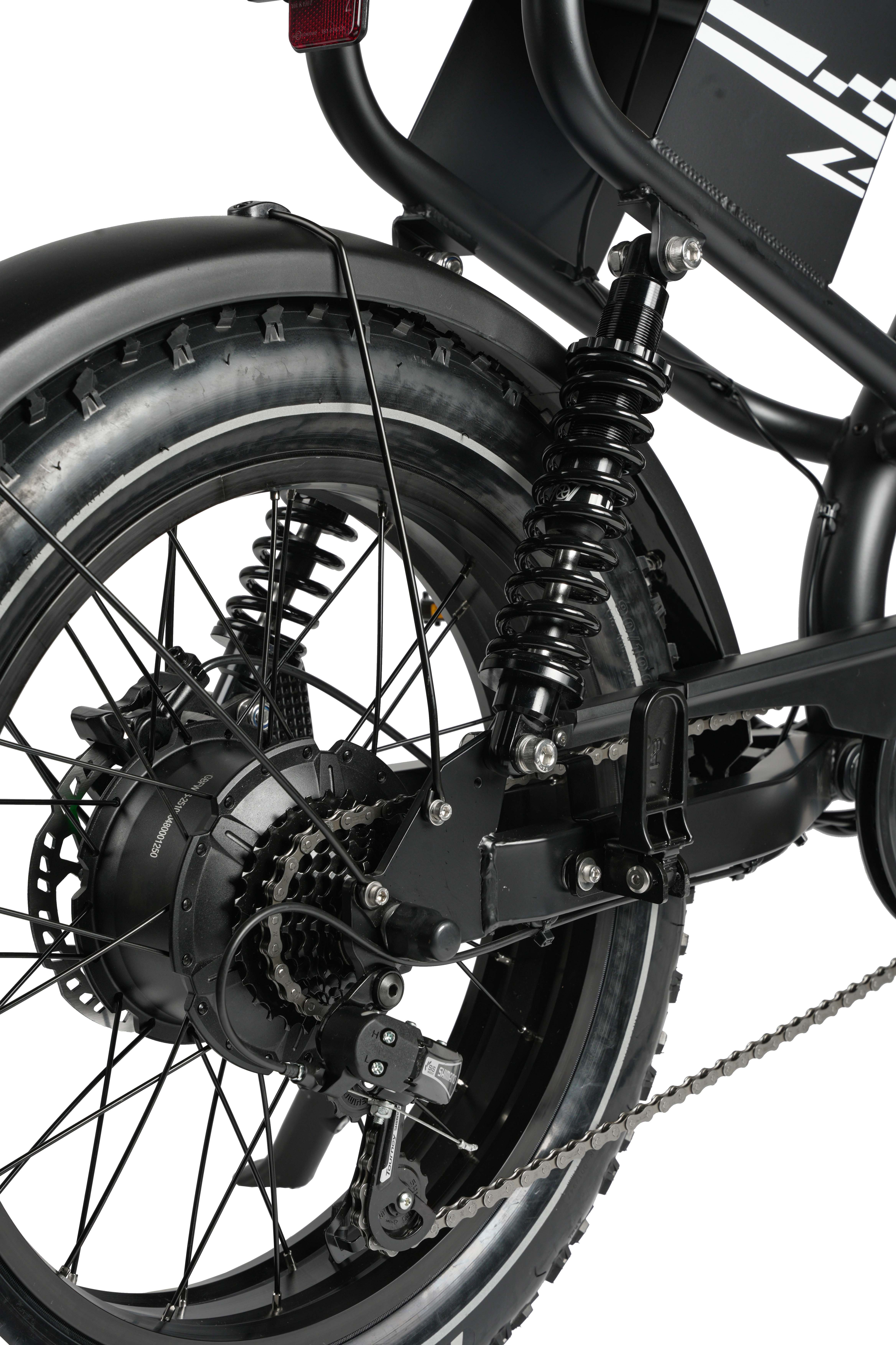 Nahaufnahme des Hinterrads eines schwarzen E-Bikes mit Stoßdämpfer und Kette.