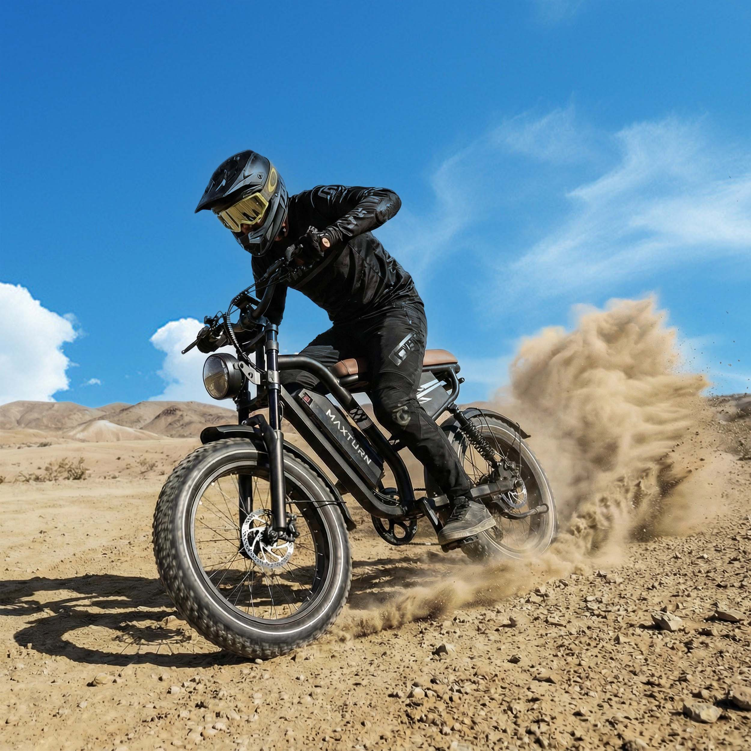 Ein Fahrer auf einem schwarzen E-Bike fährt durch Sand und wirbelt Staub auf.