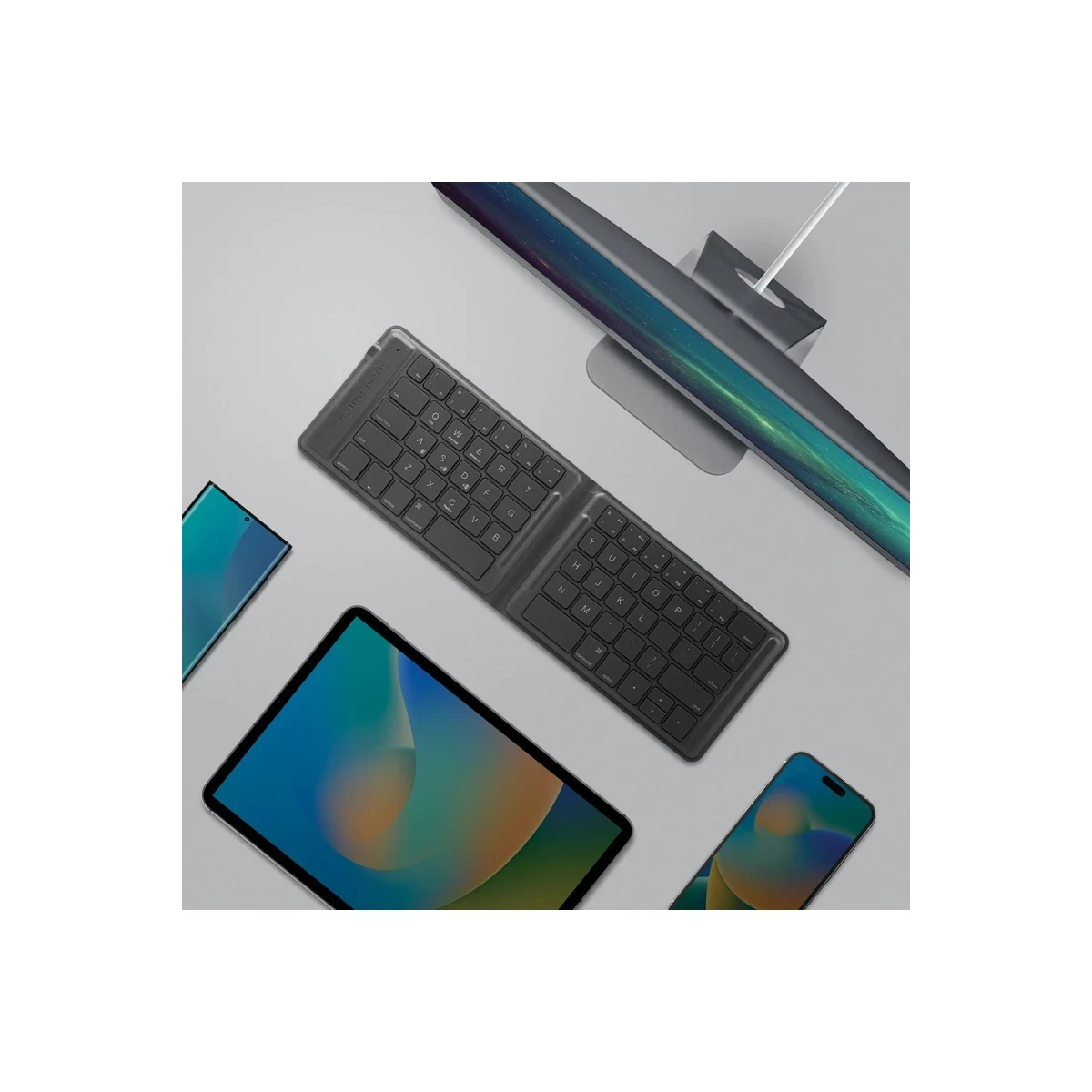 Tastiera pieghevole, tablet e smartphone su superficie grigia.