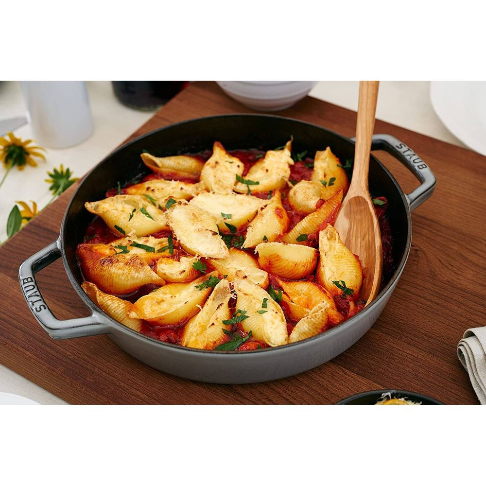 Gefüllte Nudeln in Tomatensoße in einer gusseisernen Pfanne mit Holzkochlöffel.