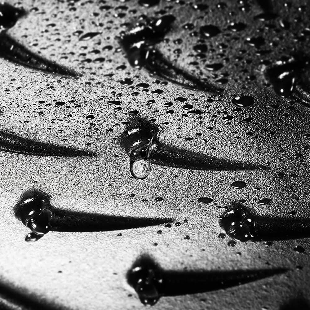 Wassertropfen auf einer strukturierten Oberfläche, im Schwarzweiß-Stil.