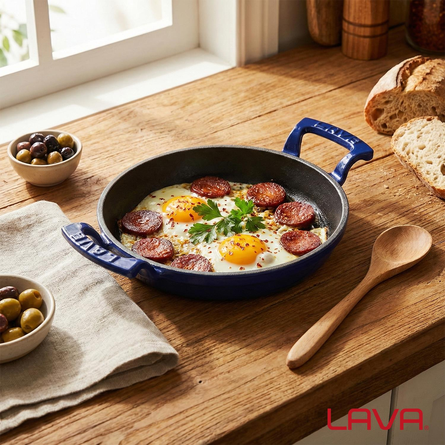 Mavi tavada sosisli sahanda yumurta, zeytin, ekmek ve tahta kaşık ile servis edilir.