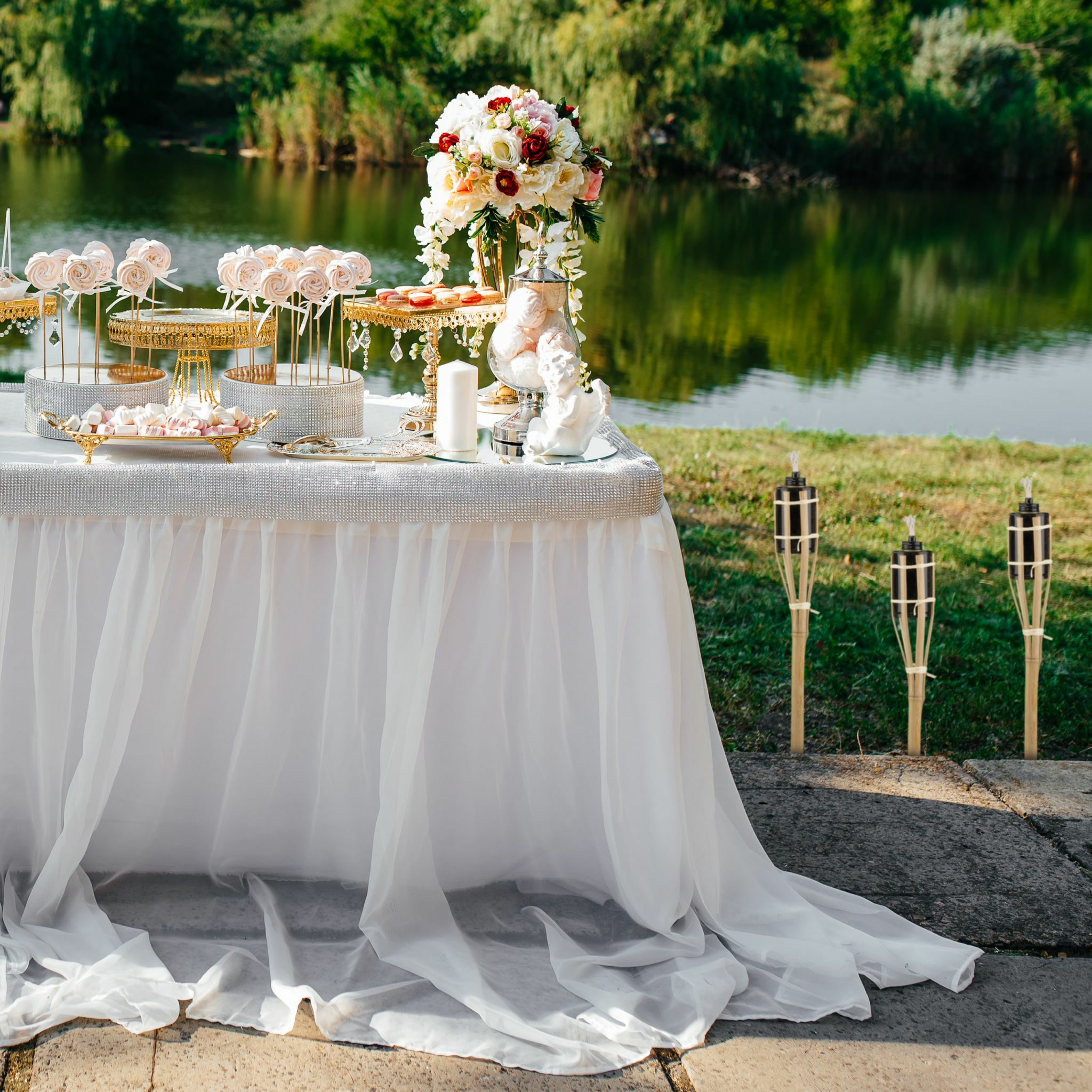 Eine festlich gedeckte Tafel mit Süßigkeiten und Blumen am Seeufer.