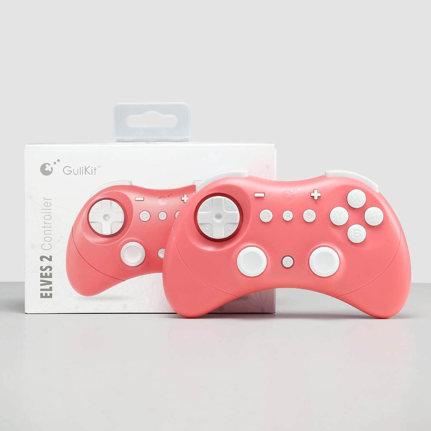 Dos mandos de juego rosa coral junto a una caja blanca con la etiqueta Gulikit.