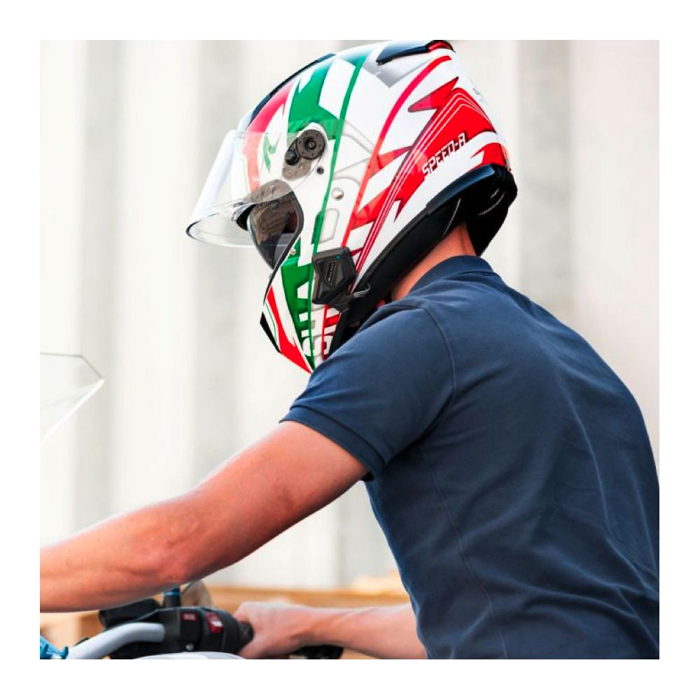 Mężczyzna w kolorowym kasku motocyklowym jedzie na motocyklu.