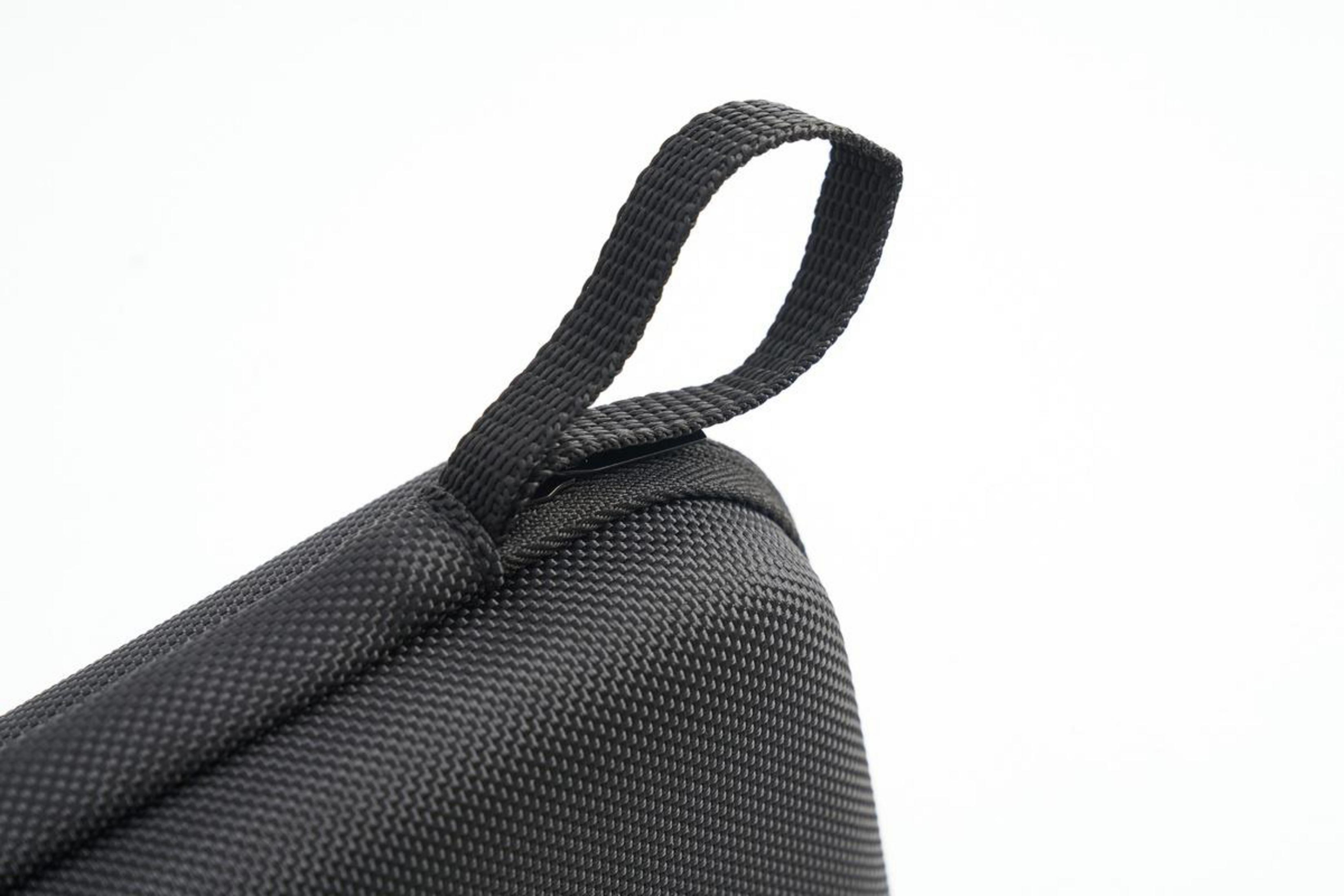 Passante in tessuto nero su cerniera di borsa su sfondo bianco.