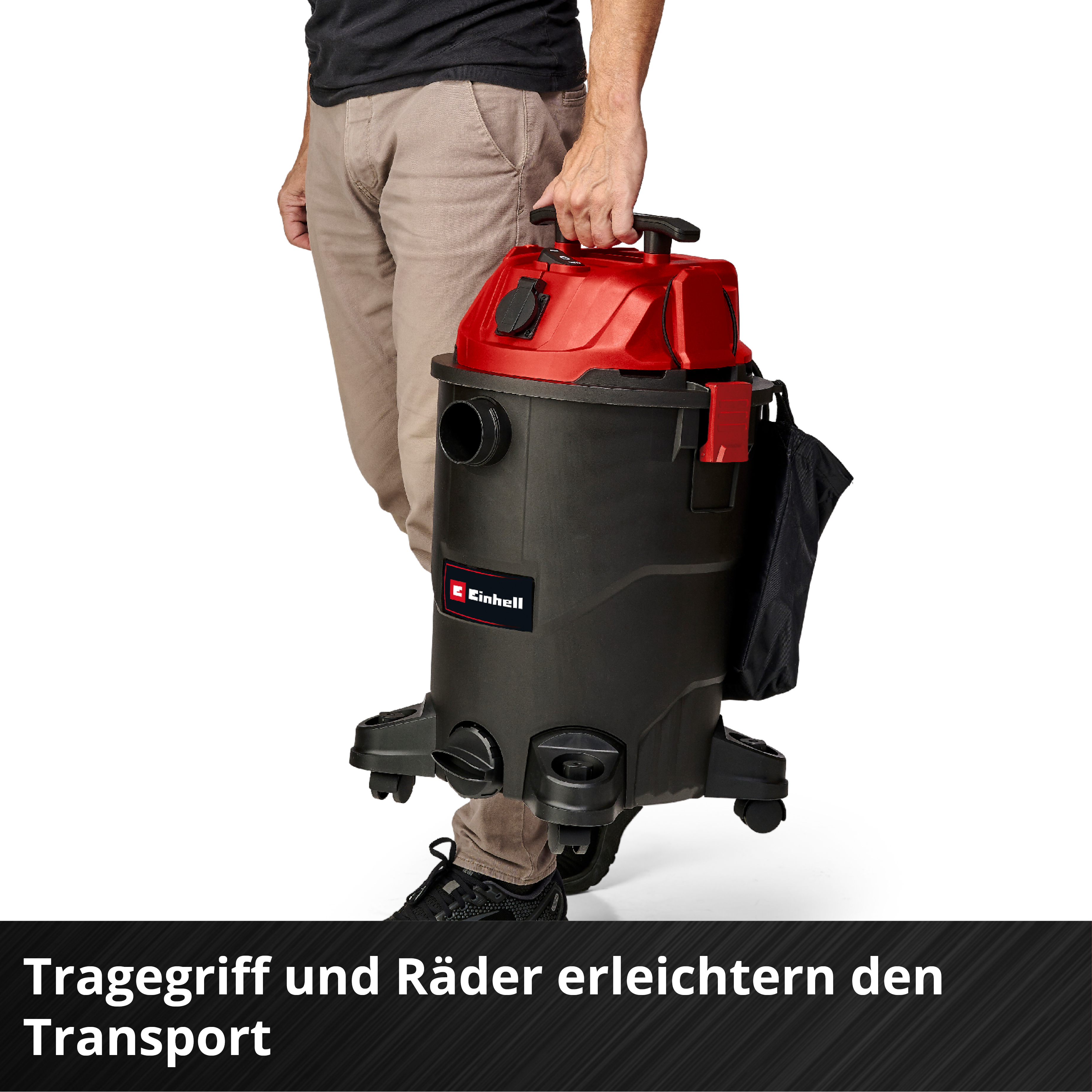 Ein Mann trägt einen schwarzen und roten Nass-/Trockensauger mit Griff und Rädern.