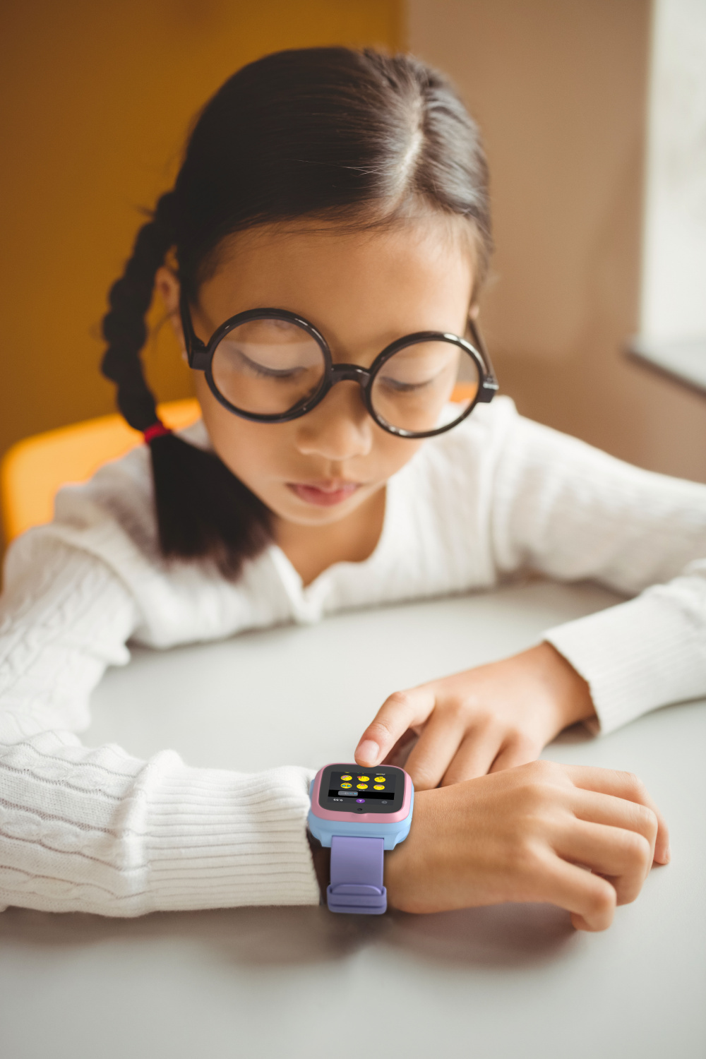 Ein Mädchen mit Brille und weißem Pullover benutzt eine lila-pinke Smartwatch.