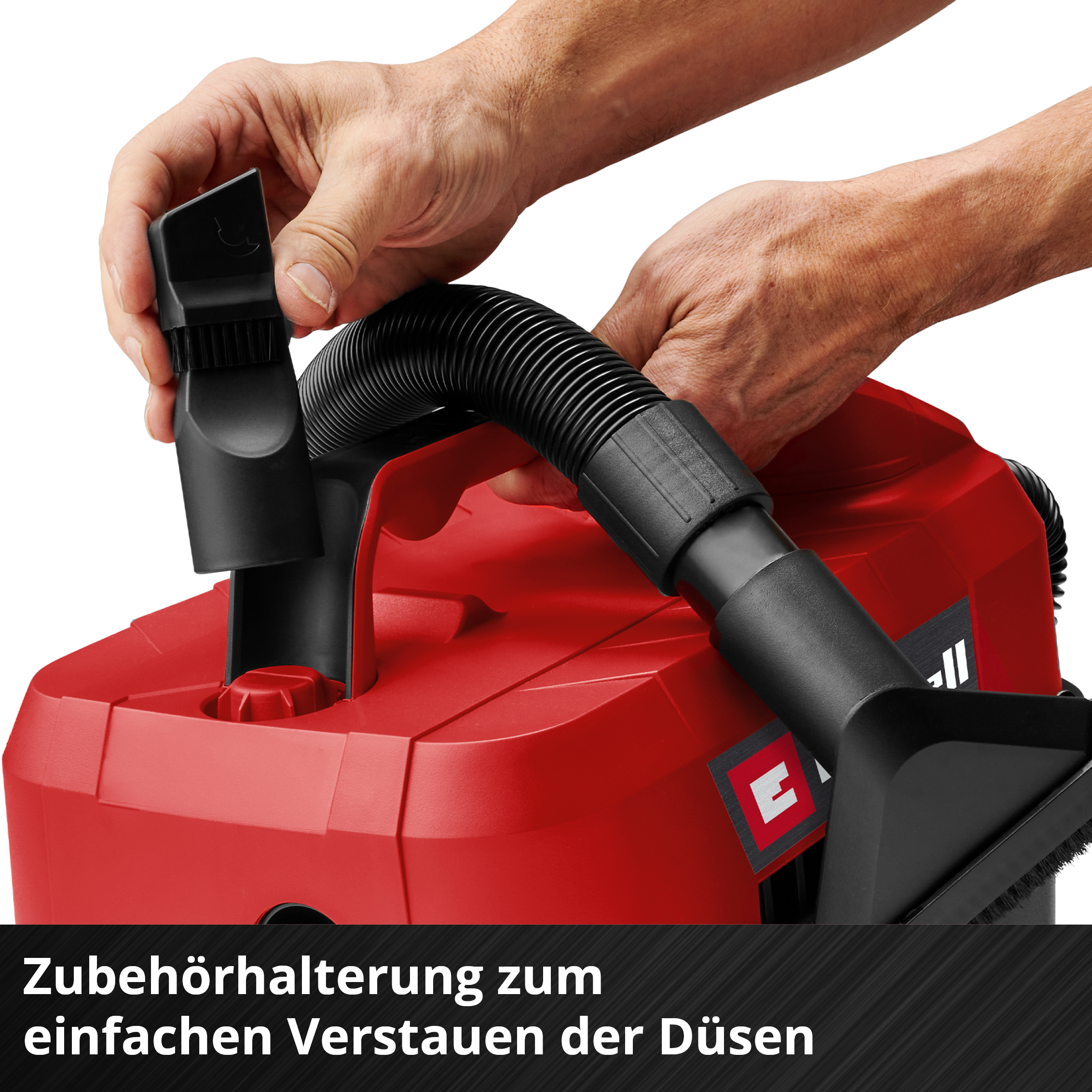 Hände verstauen ein schwarzes Saugdüsen-Zubehör in einen roten Staubsauger.