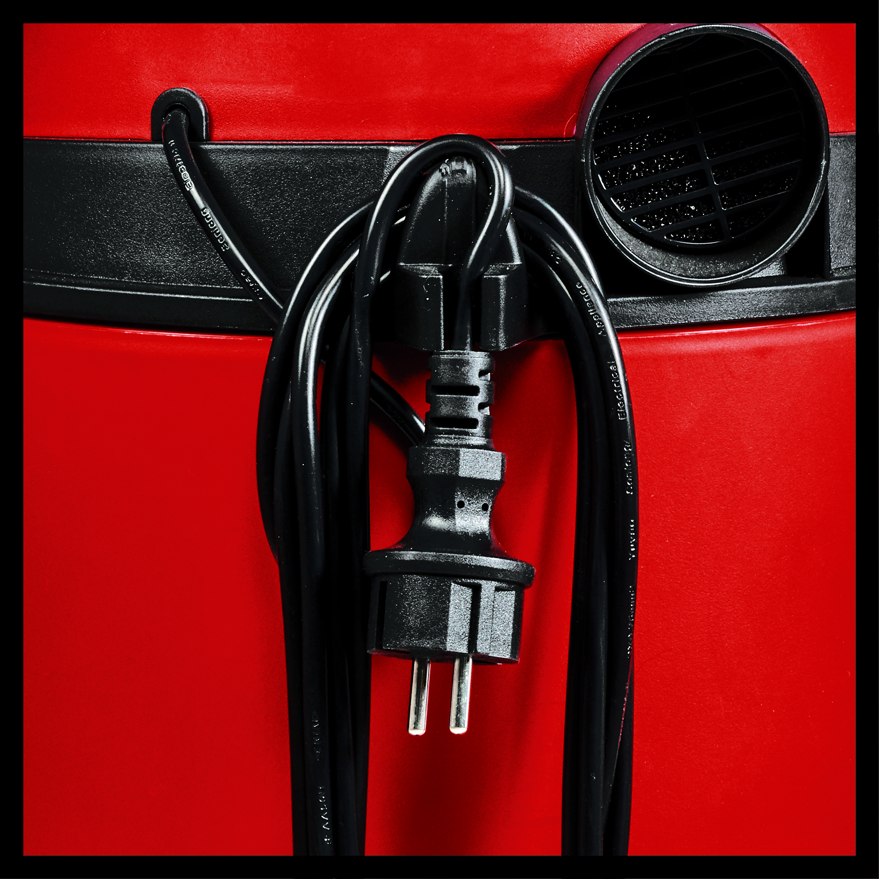 Roter Staubsauger mit schwarzem Kabel und Stecker, Nahaufnahme.