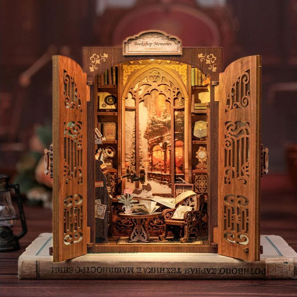 Hölzerne Miniatur-Buchhandlung mit offenen Türen, Büchern, Möbeln und Winterlandschaft.