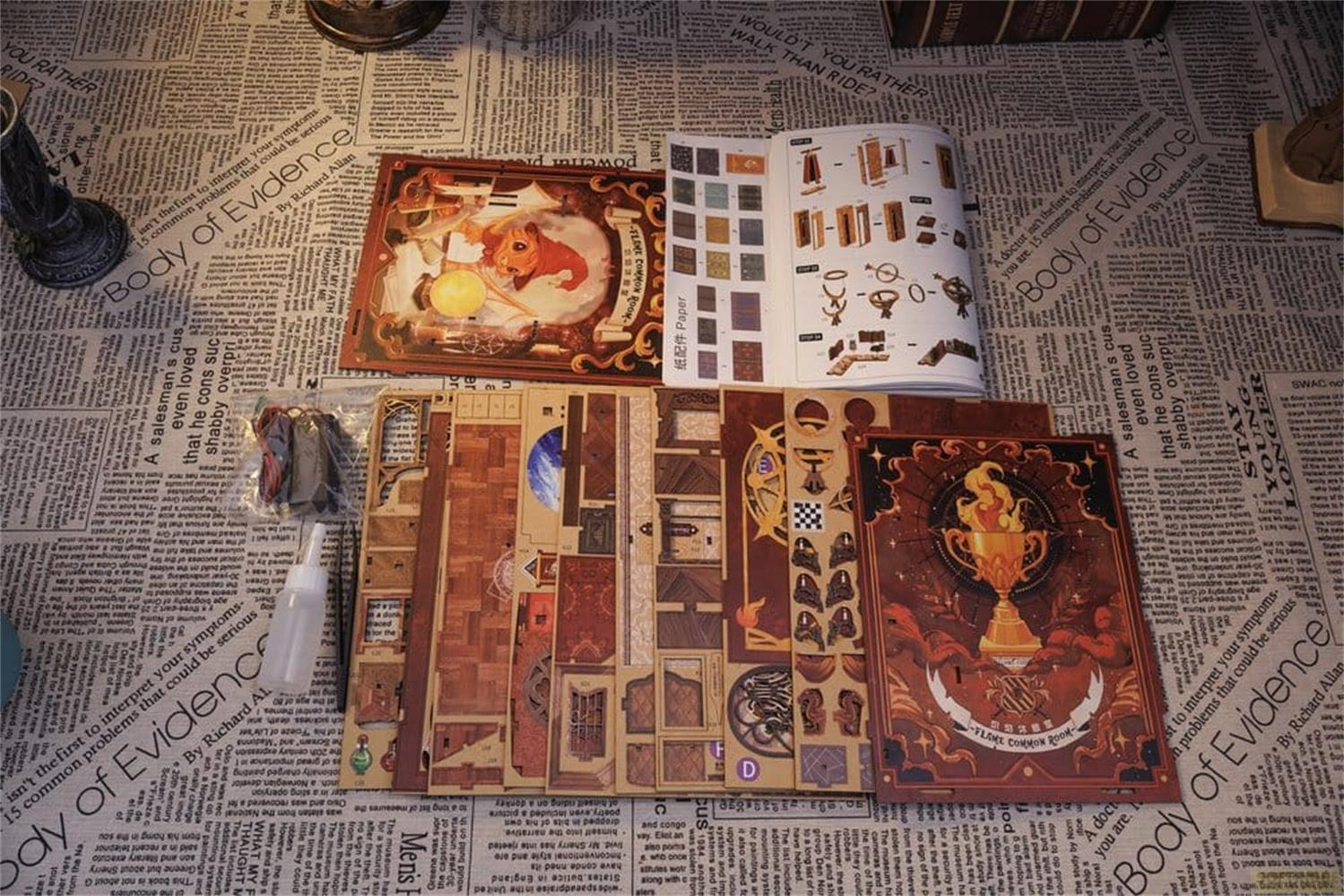 Kit de bricolage avec livre sur fond de journal, montrant des pièces de modèle.