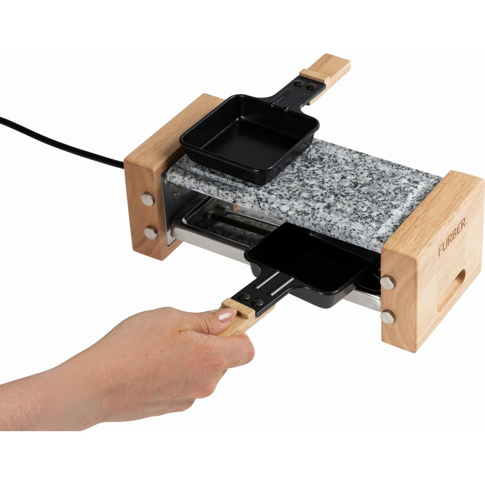 Ein Raclette-Grill mit Holzrahmen, Steinplatte und zwei Pfännchen.