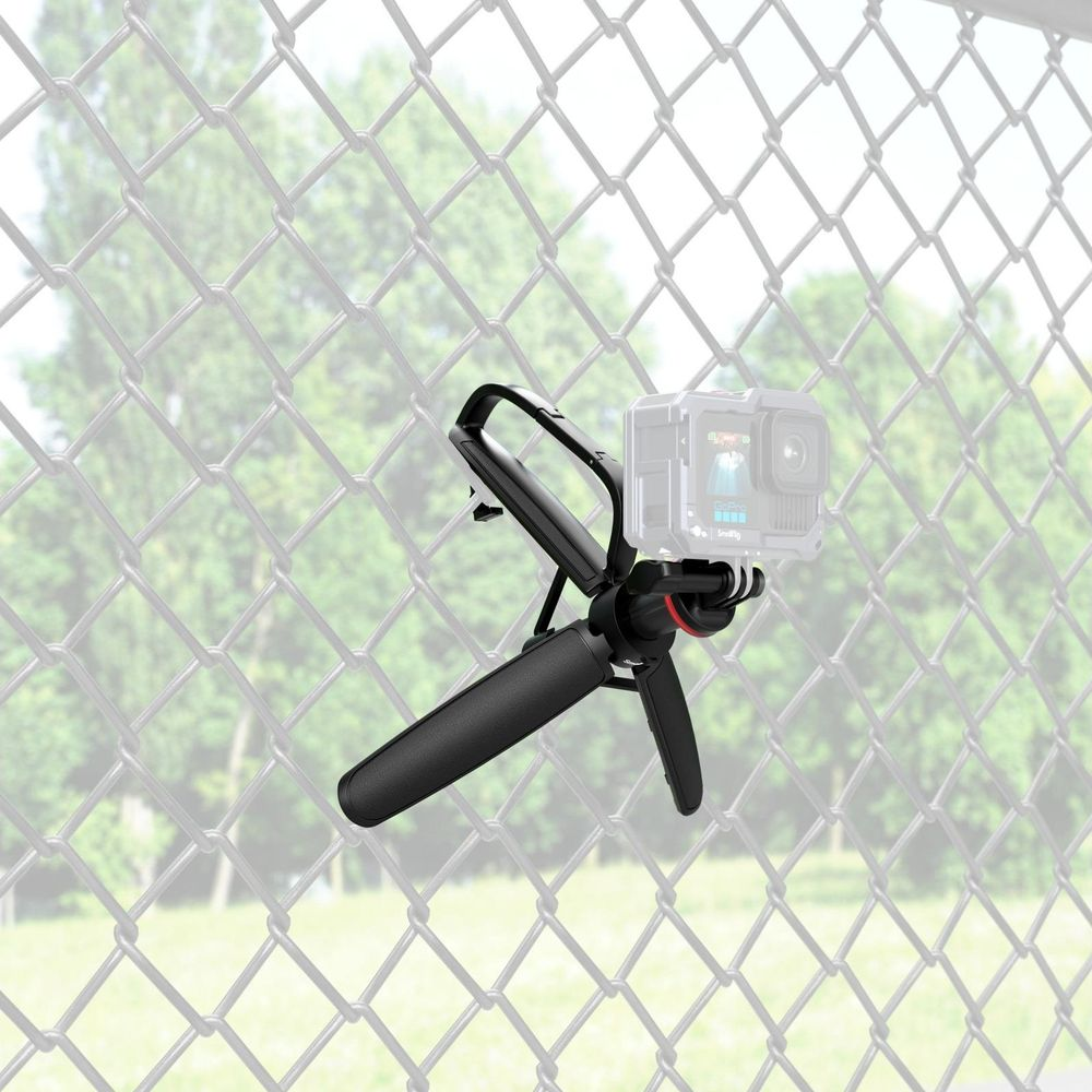 Un mini trépied noir avec une caméra d'action attachée à une clôture en grillage.